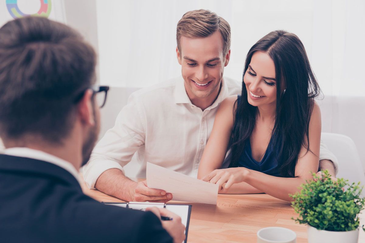Three people reviewing documents at a table in a bright office