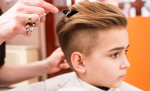 A young boy is getting his hair cut at a barber shop.