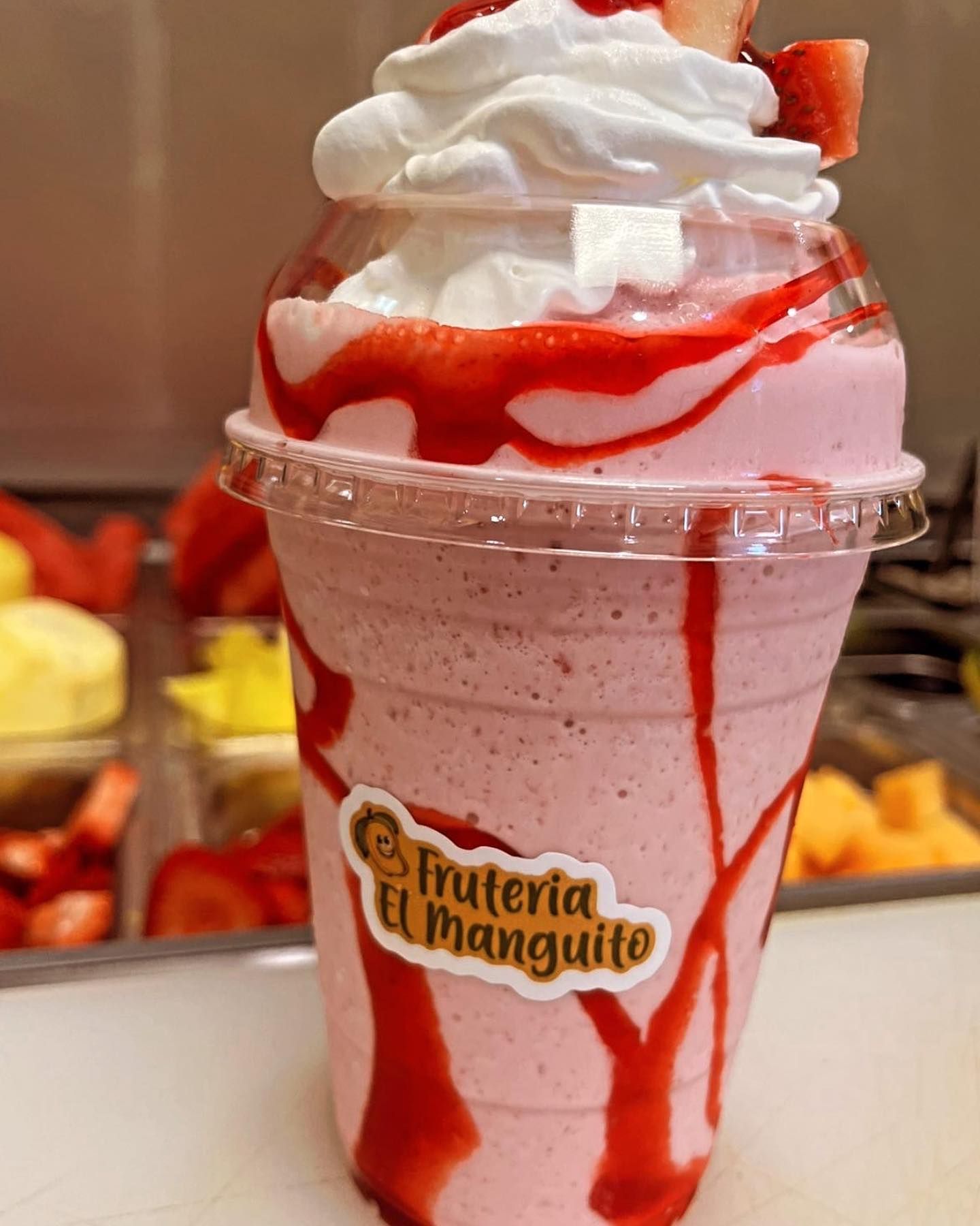 A cup of strawberry milkshake with whipped cream and strawberries on top