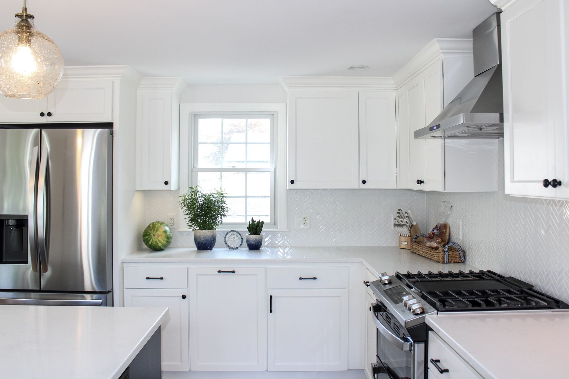White kitchen with stainless steel appliances, white cabinets, and white countertop.