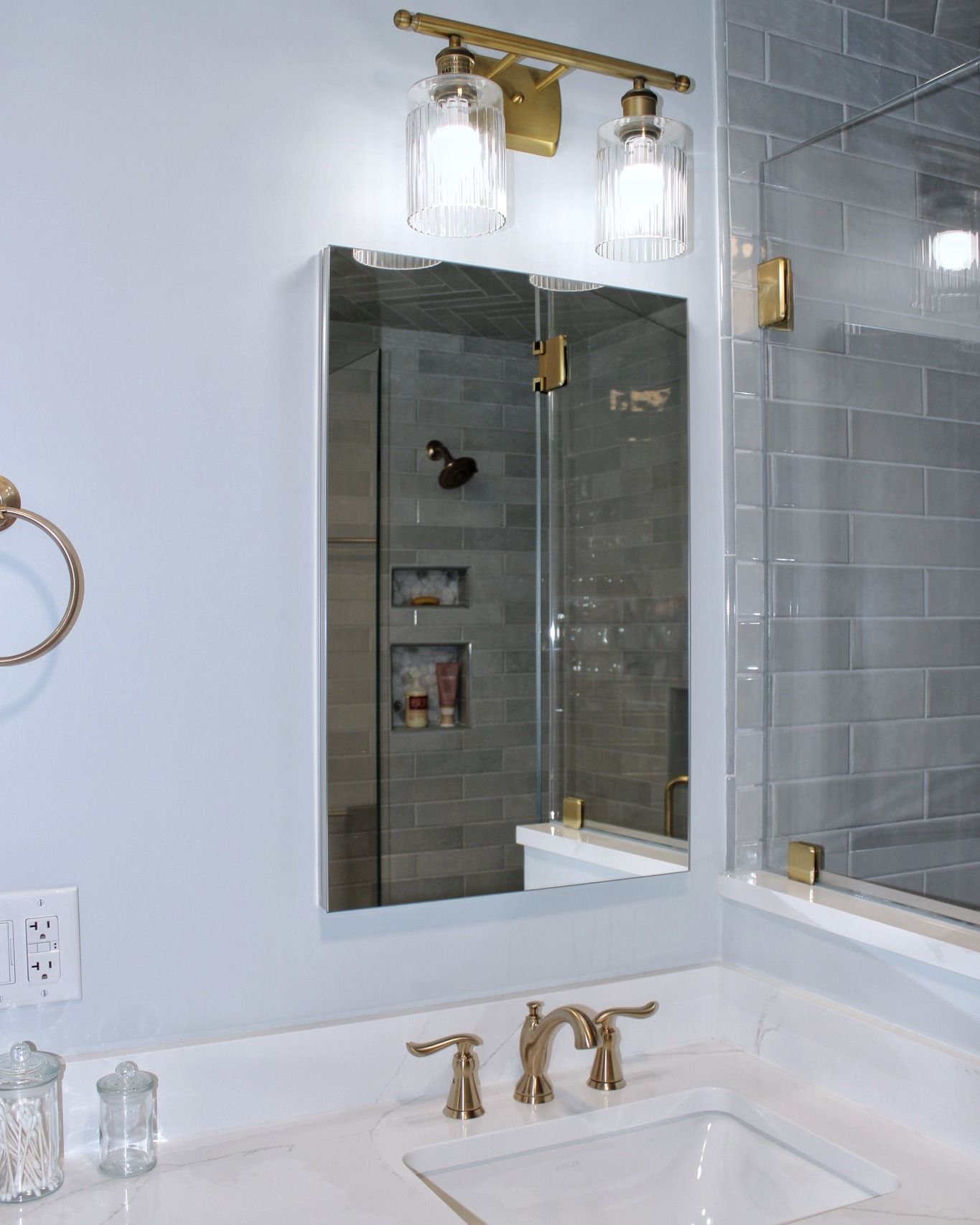 Bathroom with vanity, mirrored medicine cabinet, and brass fixtures.