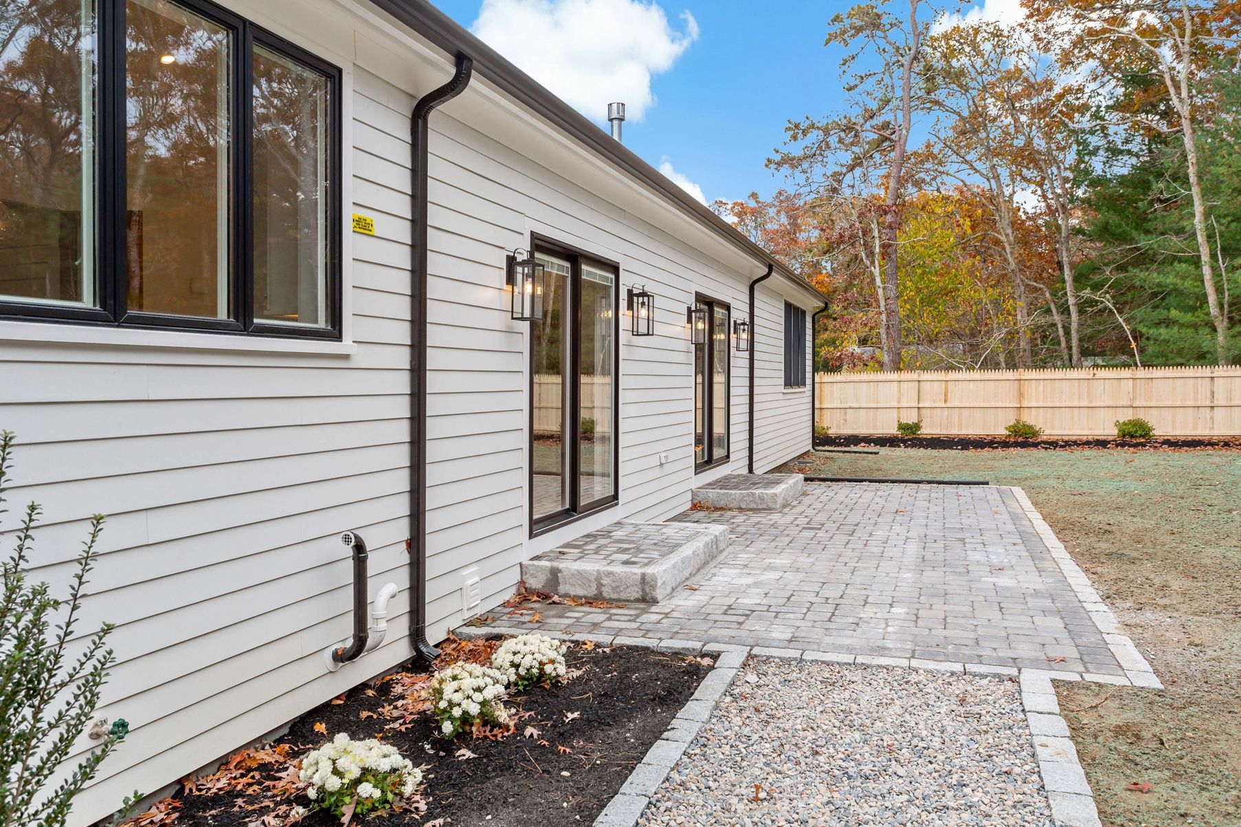 White house exterior with patio, black trim, and a gravel walkway.