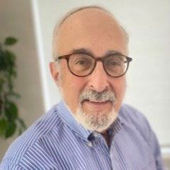 A man with glasses and a beard is smiling for the camera.