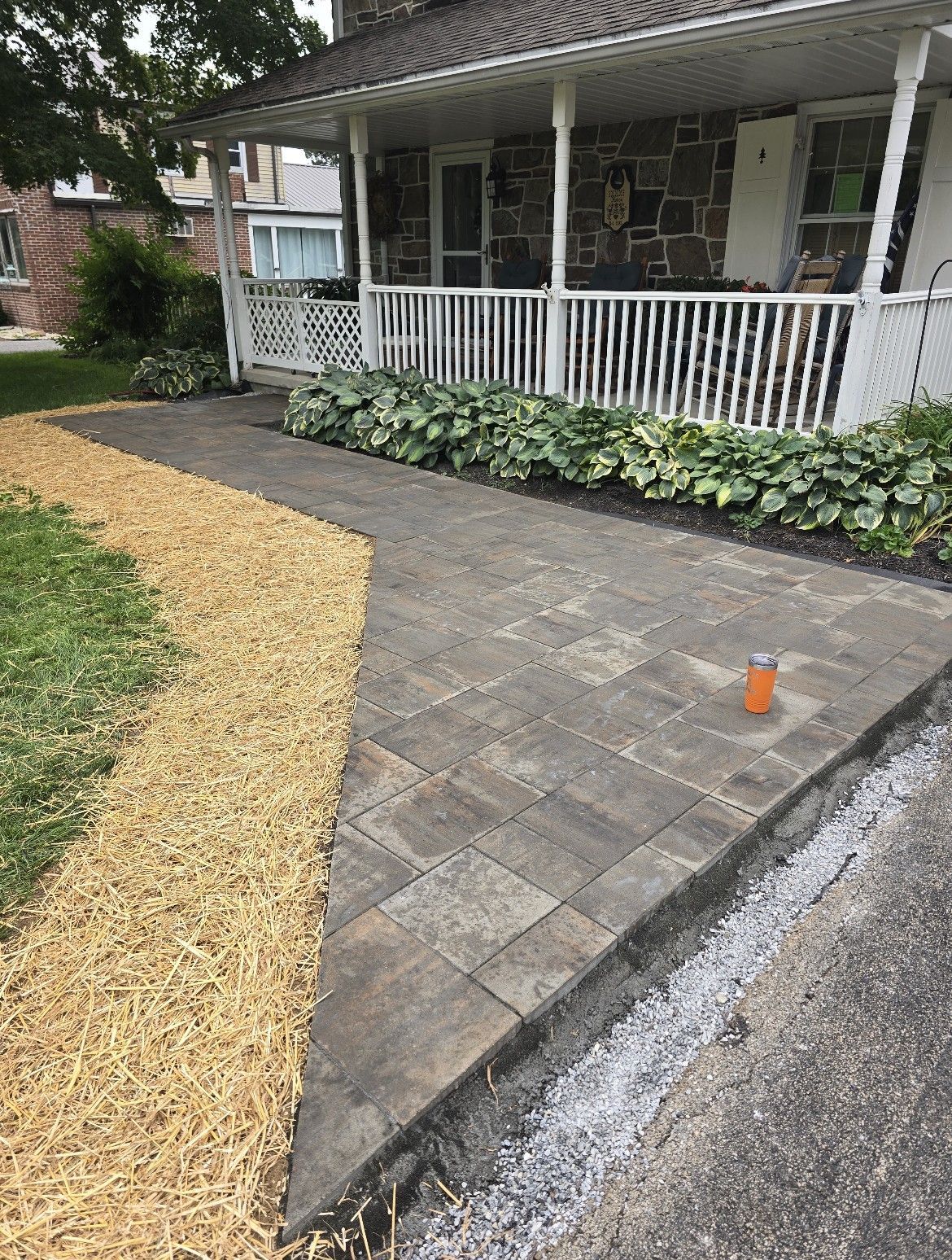 New stone paver walkway beside a house porch, with gravel edging and plants along the side.