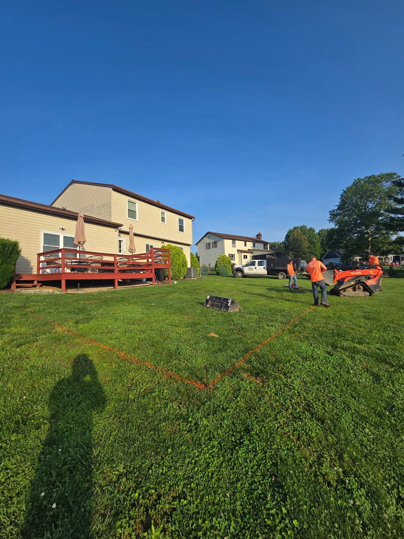 A group of people are standing in a grassy field in front of a house.