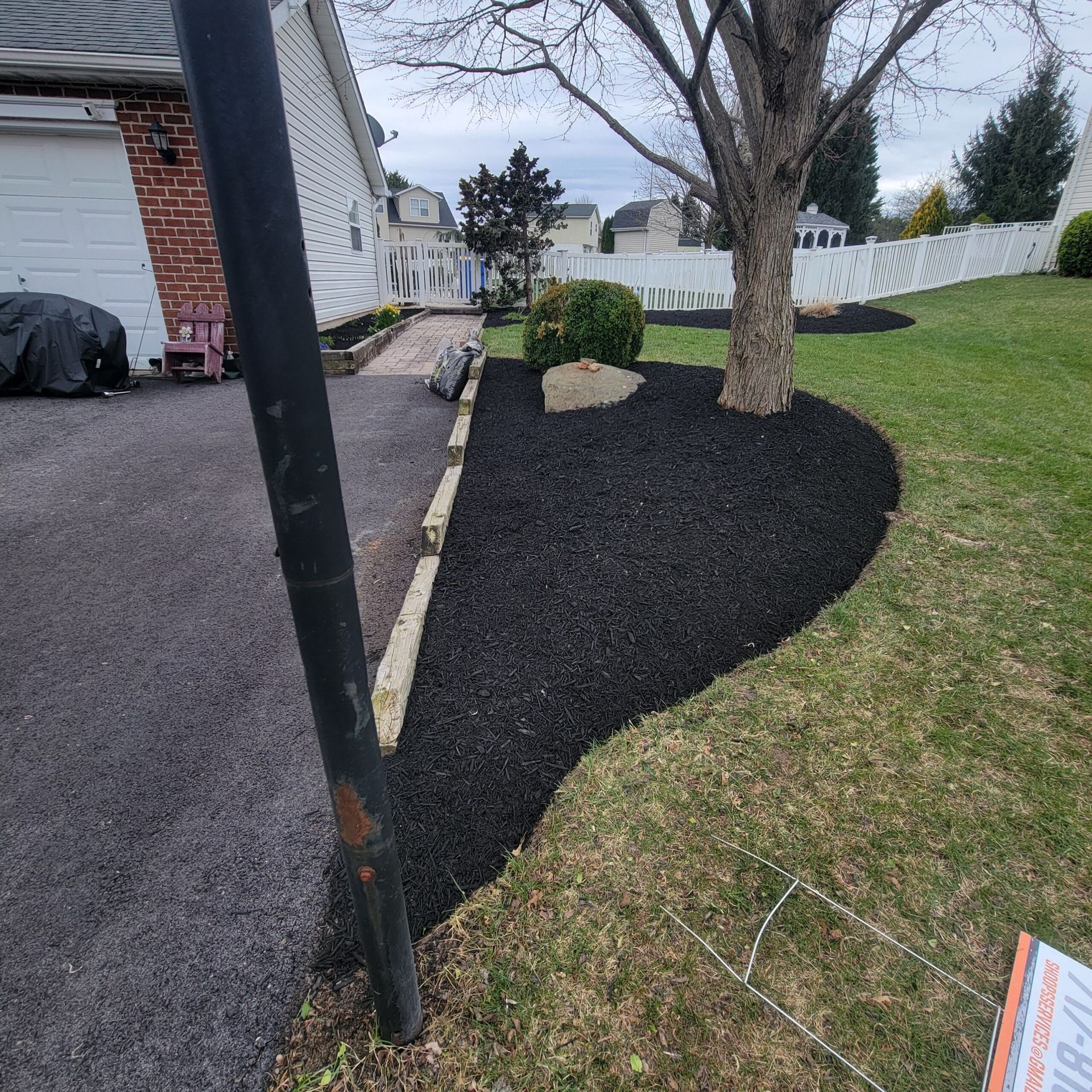 A yard with black mulch and a tree in the middle