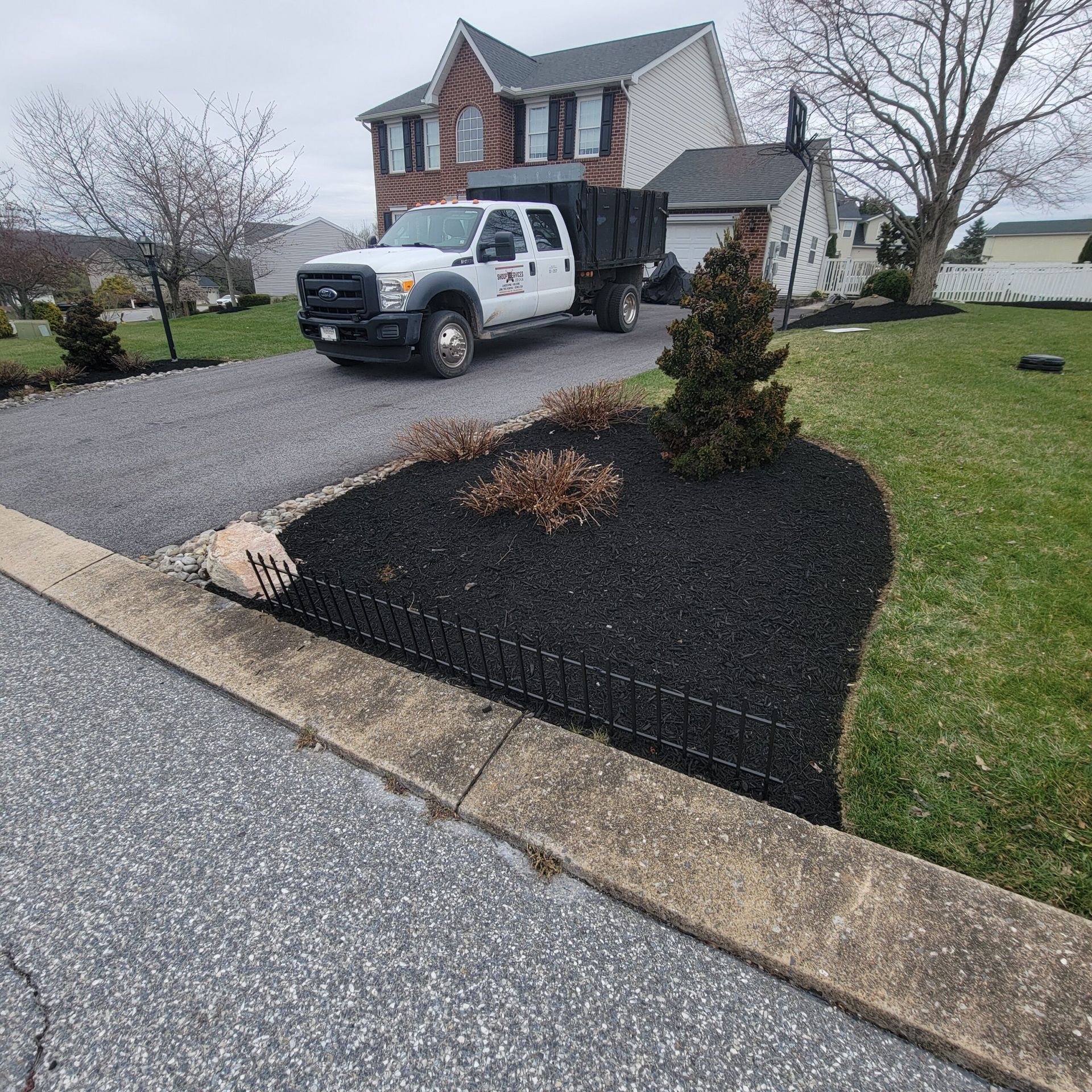 A white dump truck is parked in front of a house.