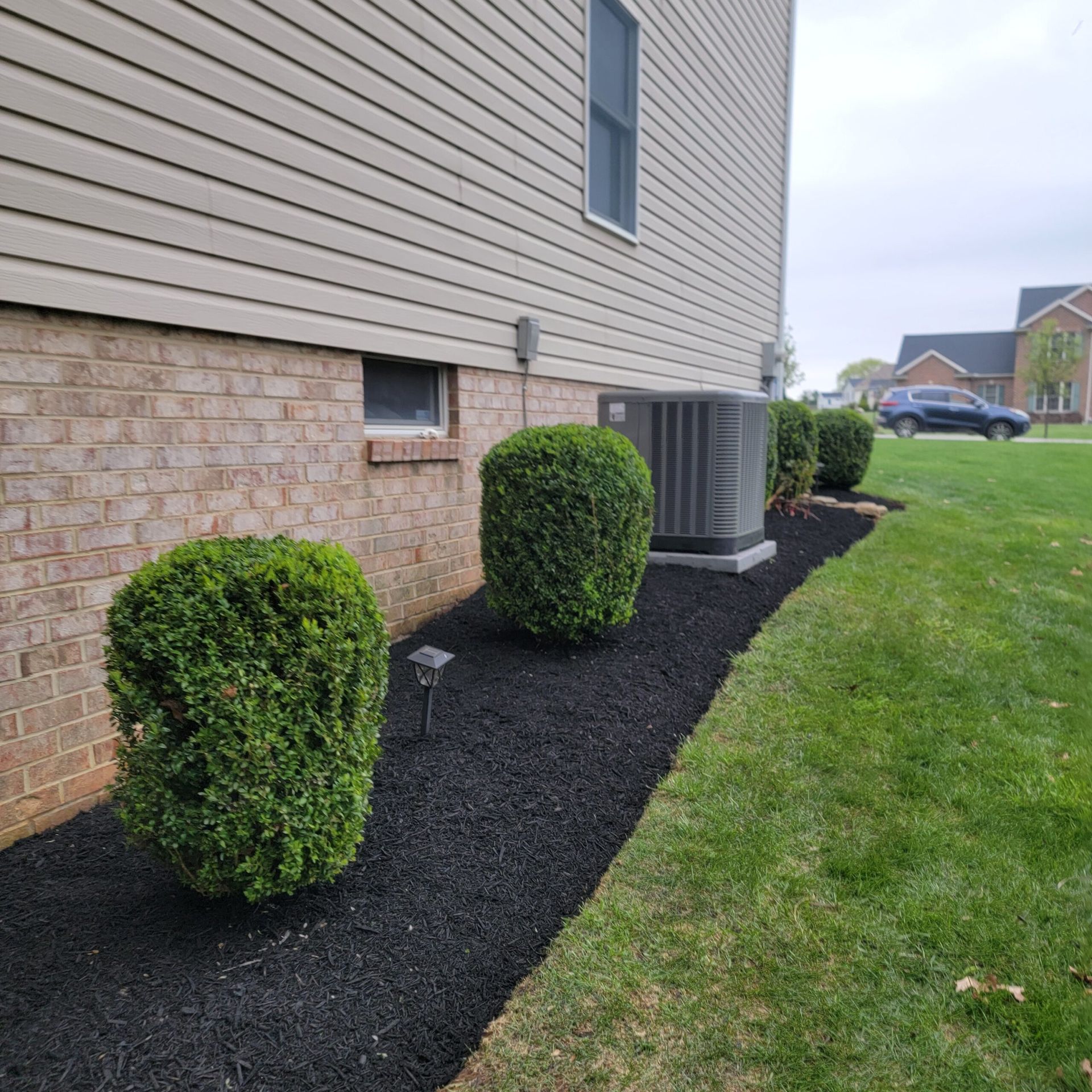A house with a air conditioner and bushes in front of it