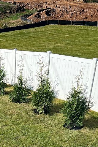 A white fence surrounds a lush green field.