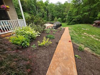 A concrete walkway leading to a house in the woods.