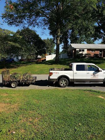 A white truck is pulling a trailer full of plants.