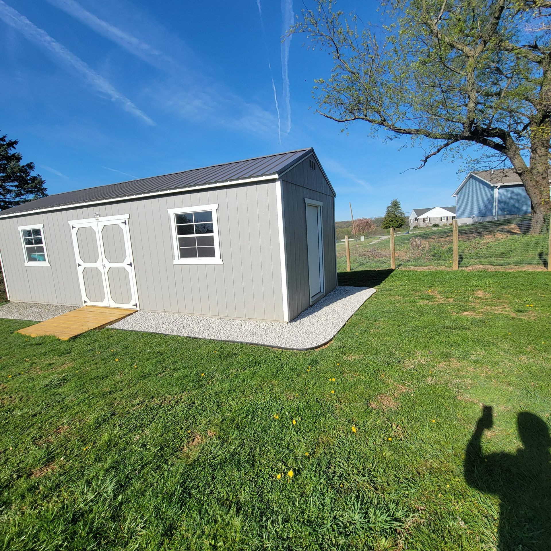A shed is sitting in the middle of a lush green field.