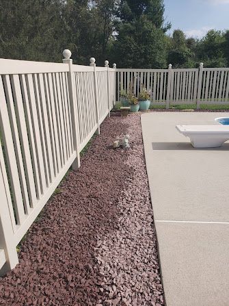 A white fence surrounds a patio and a pool.