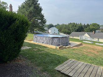 A swimming pool is sitting in the middle of a lush green field.