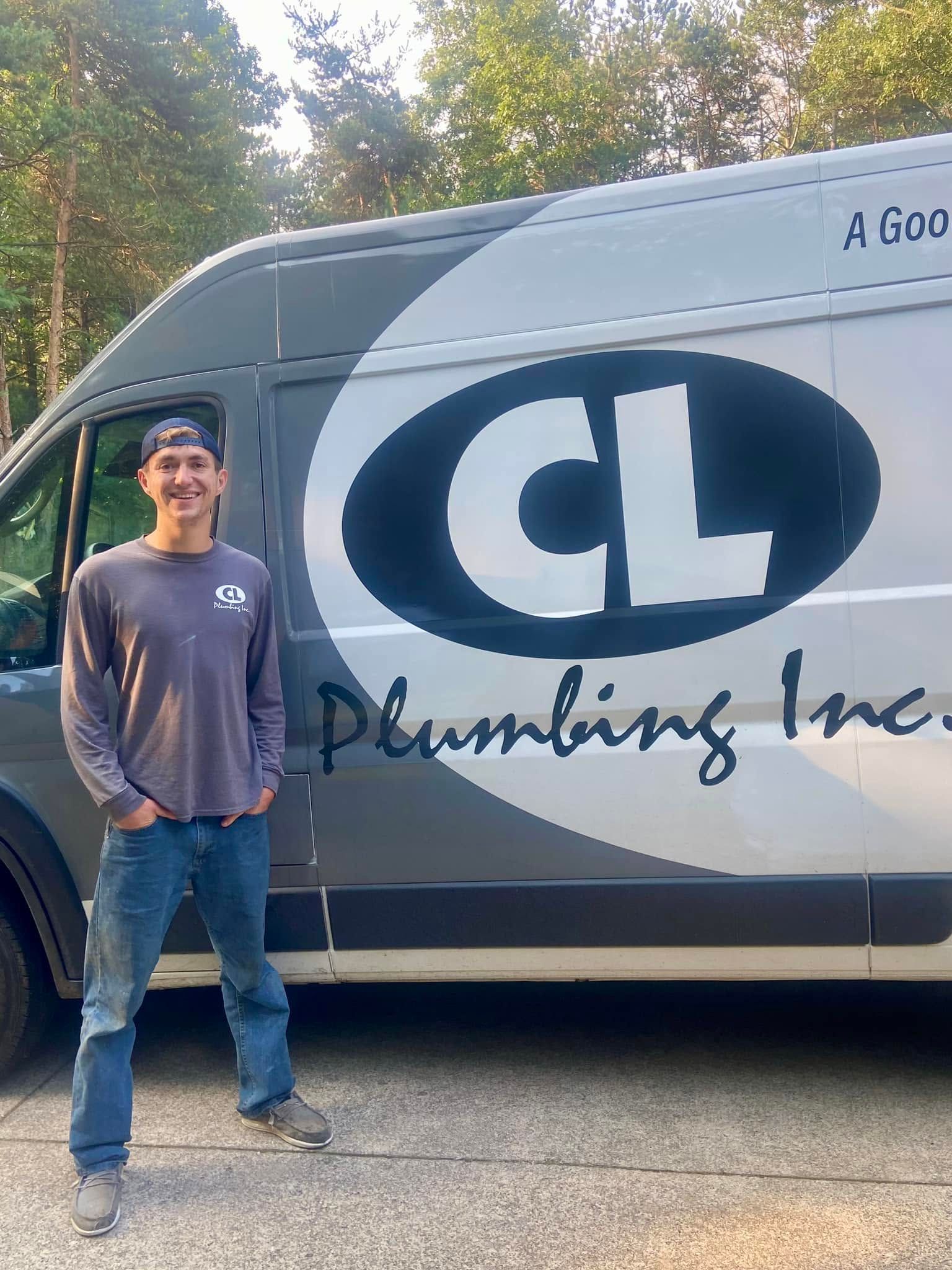 Person standing beside a CL Plumbing Inc. van in a wooded outdoor area.
