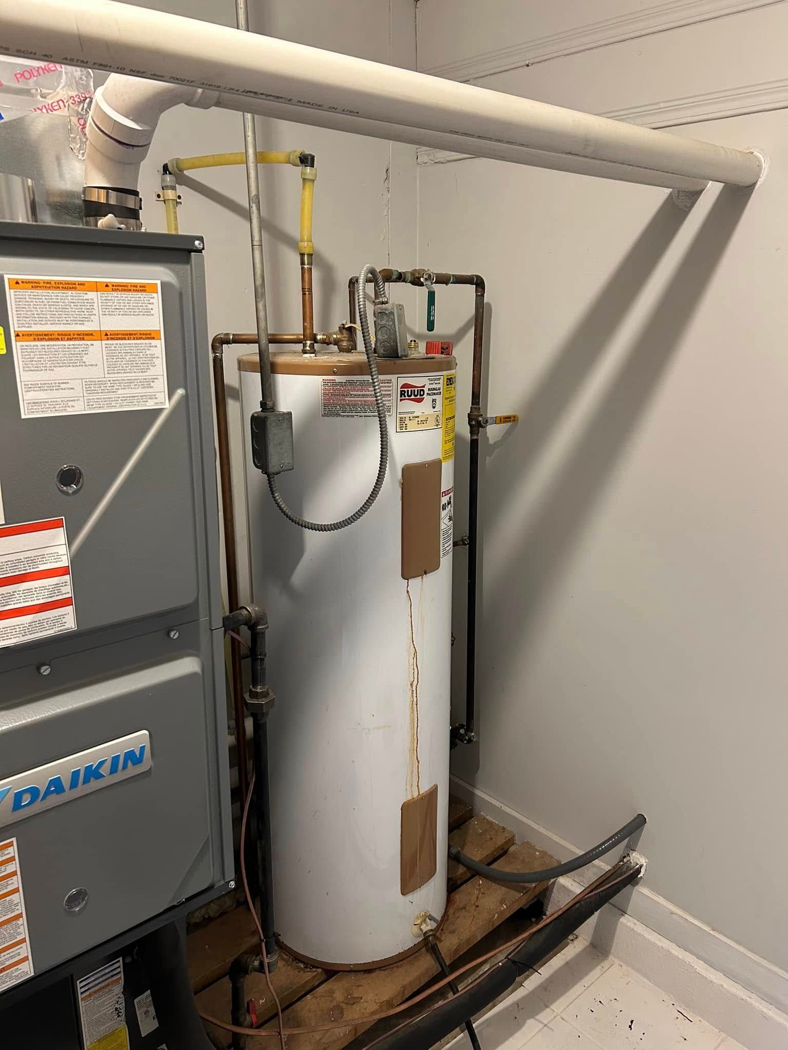 Water heater and HVAC furnace in a utility closet with exposed pipes and venting.