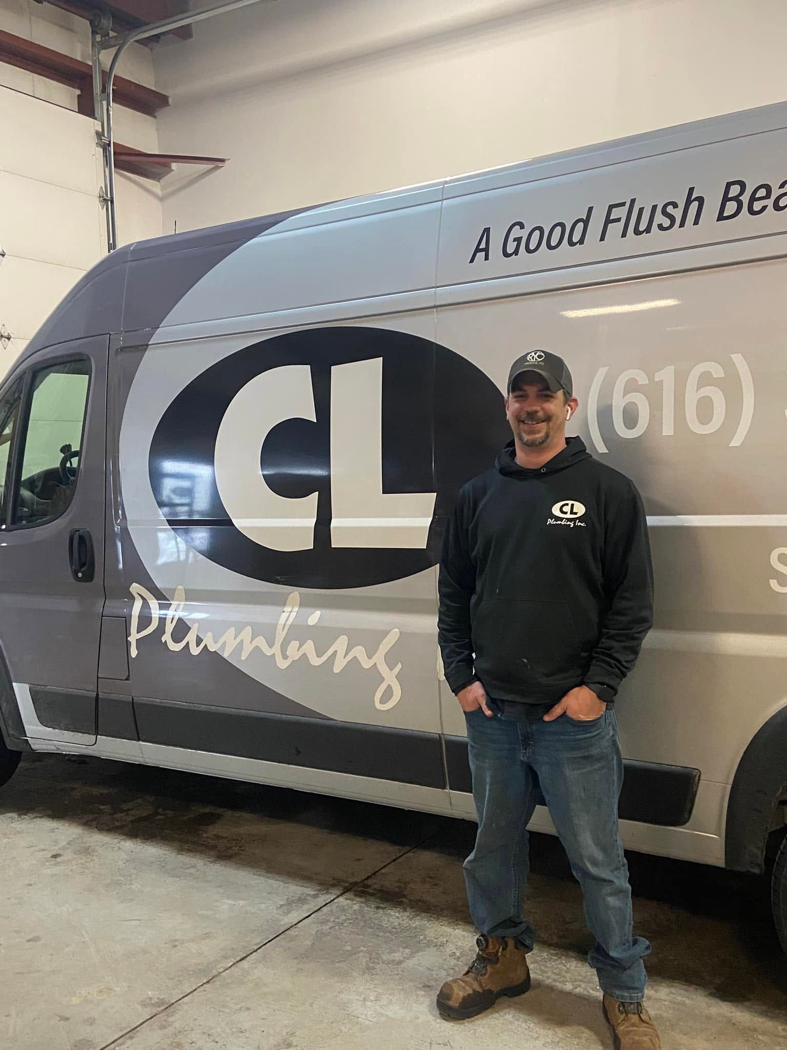 Man standing beside a gray plumbing service van with large “CL” logo in a garage.