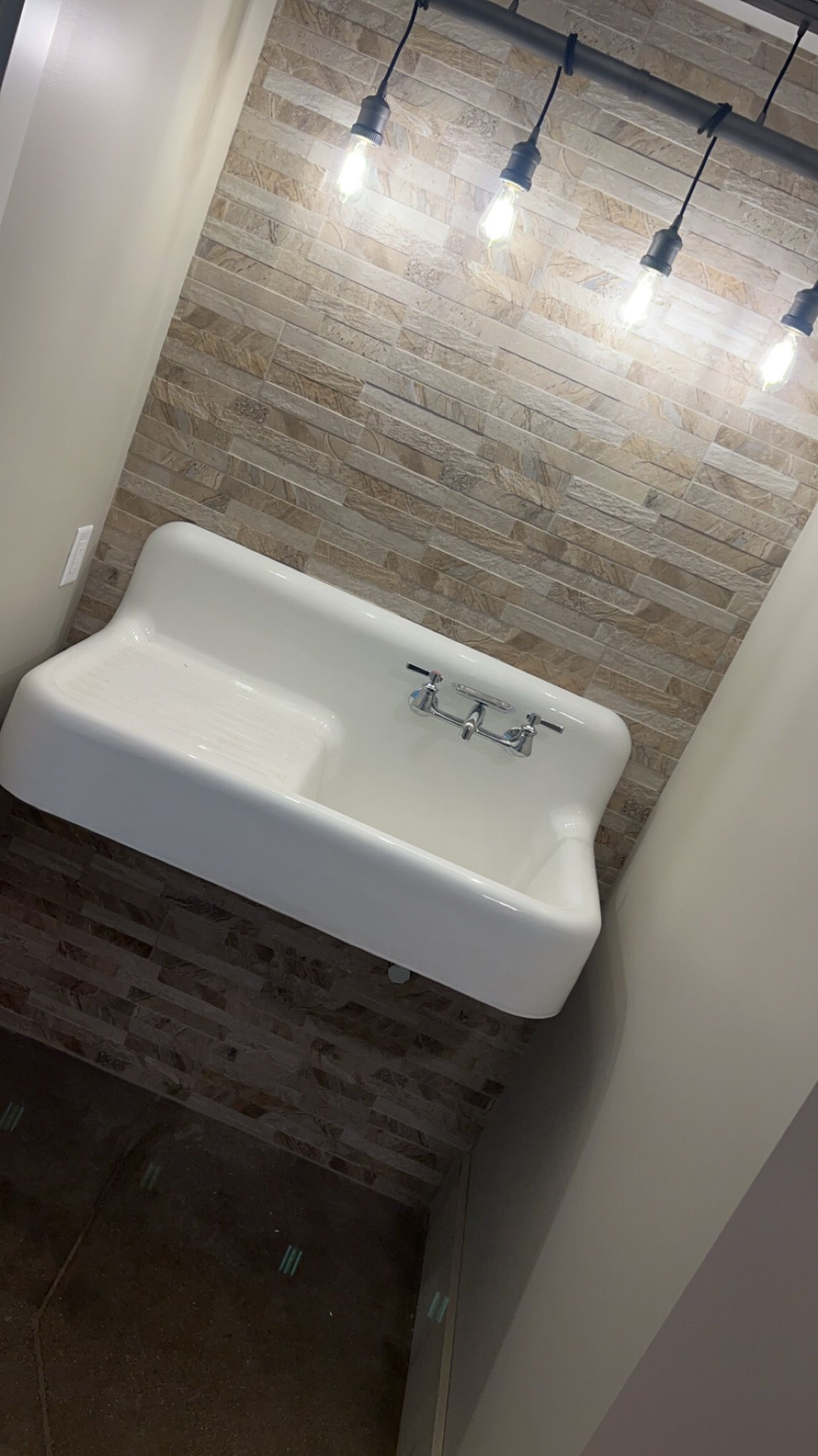 Small bathroom with a white wall-mounted sink, brick-pattern tile, and pendant lights overhead.