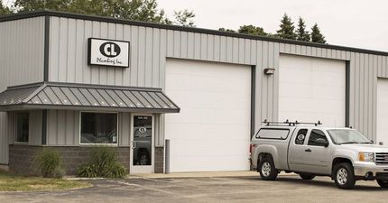 Industrial building with a garage bay, office entrance, and a parked pickup truck outside
