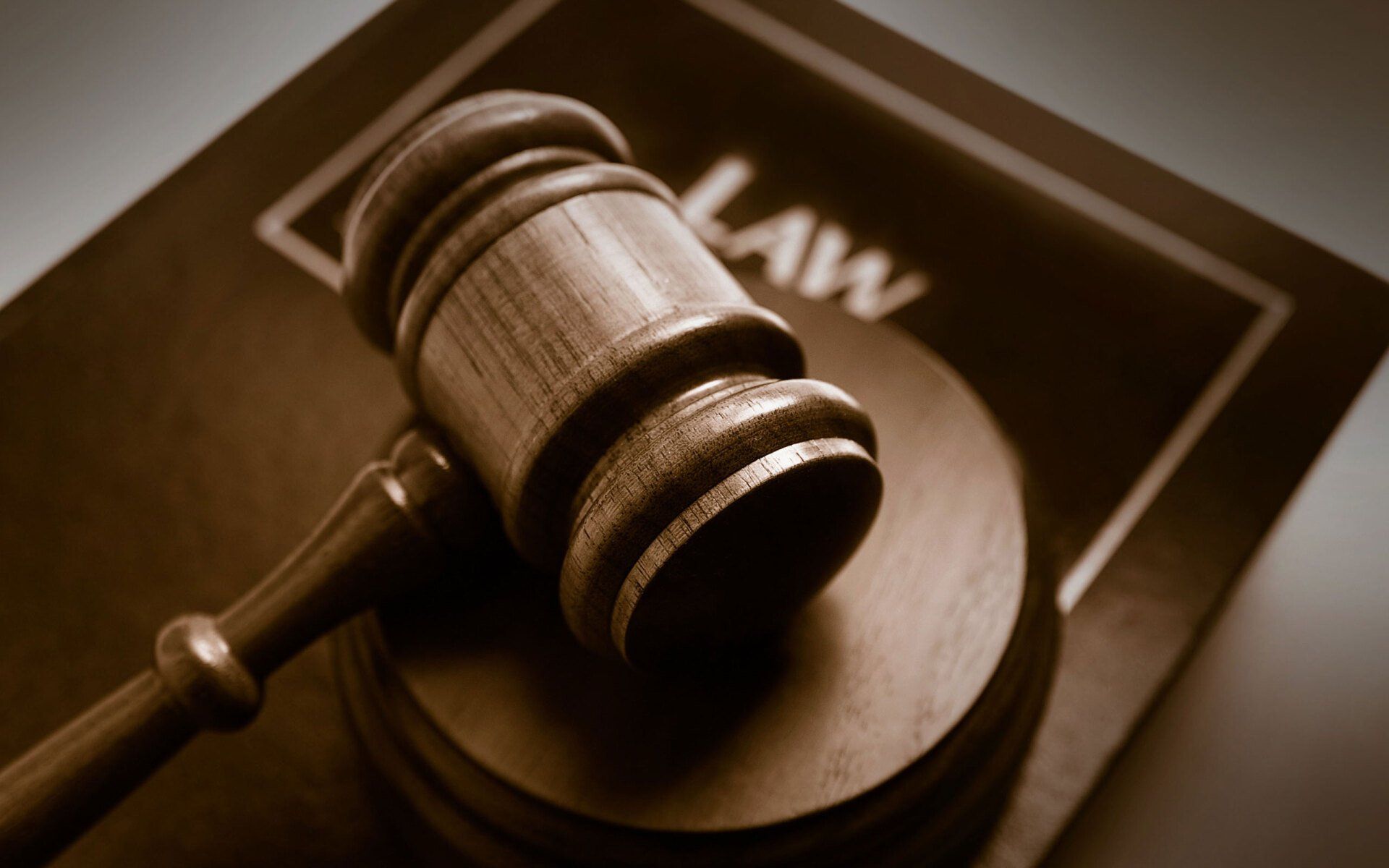 A wooden gavel resting on a sounding block atop a book titled 