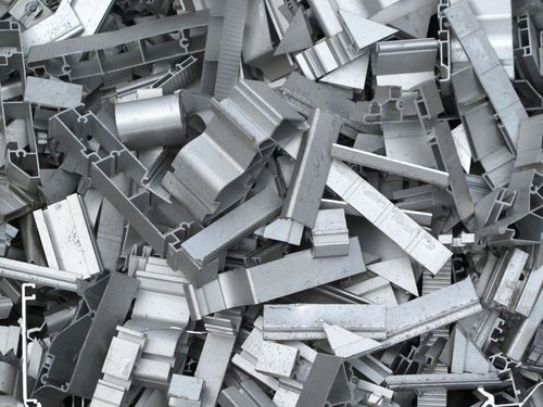 Pile of shiny metal scrap pieces stacked together in a cluttered industrial setting