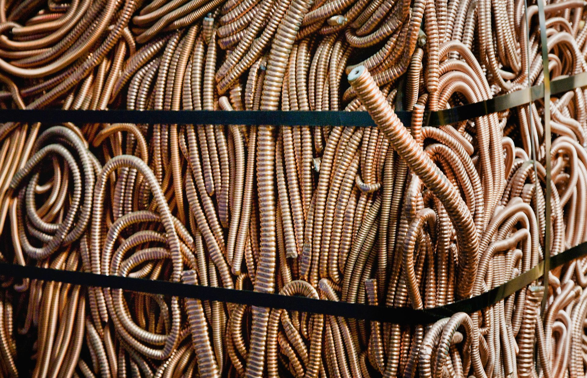 Coiled tan ropes bundled in a stack, held together with black straps.