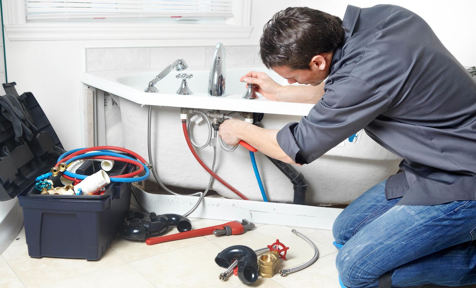 A plumber is working on a bathtub in a bathroom.