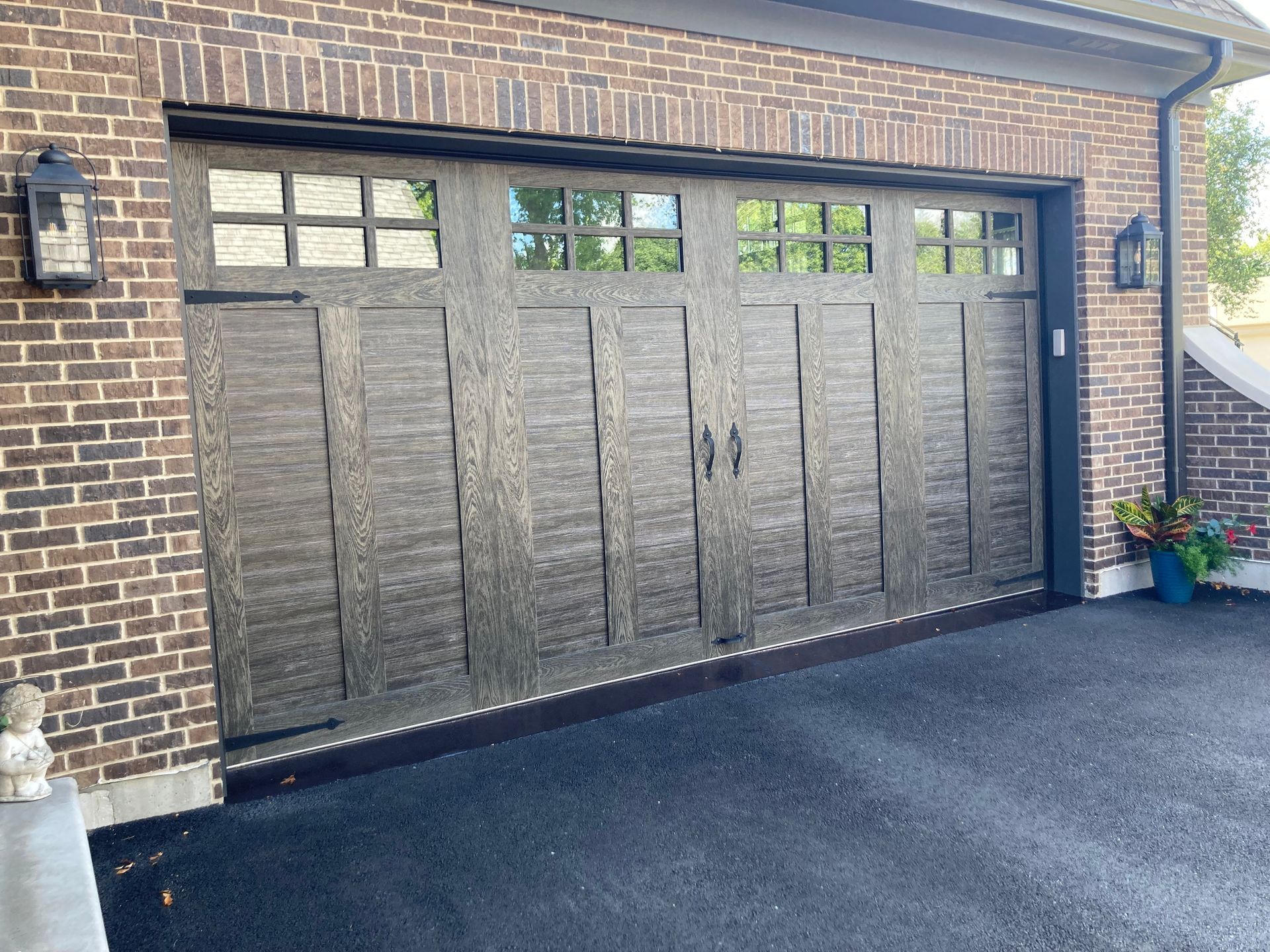 a garage door with a brick wall and a black driveway