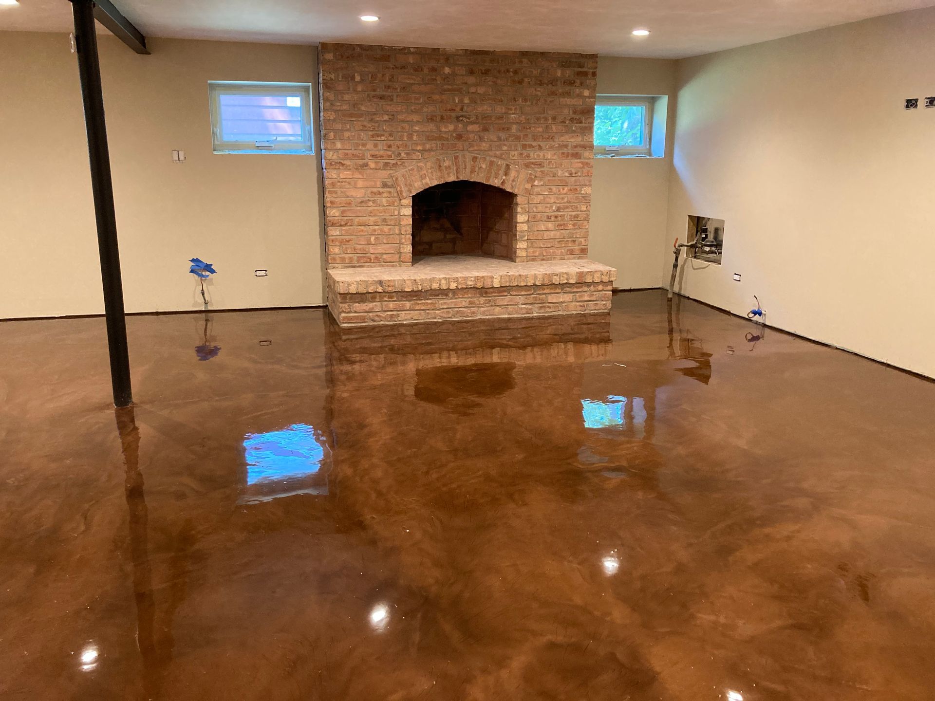a living room with a brick fireplace and a shiny concrete floor