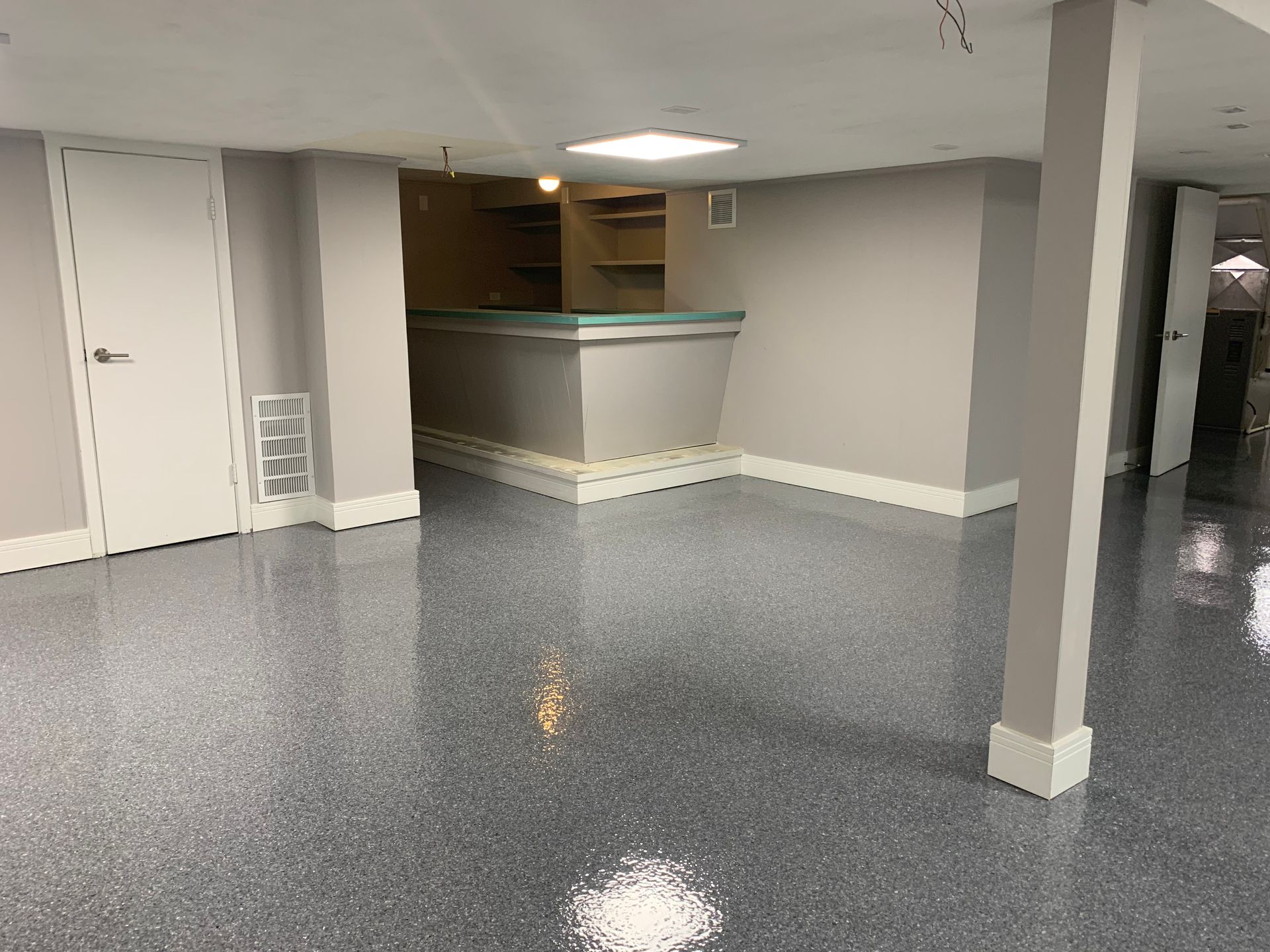 a basement with a bar and a gray floor