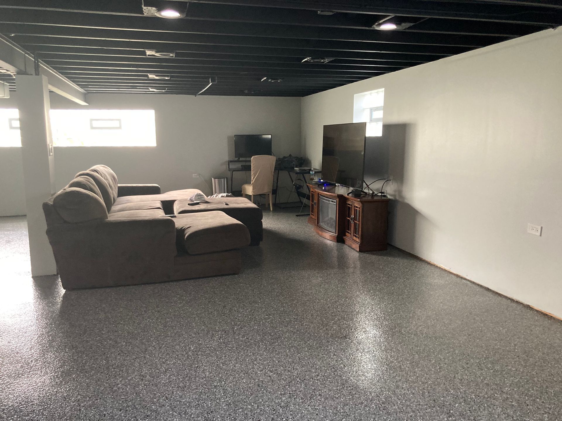 a living room in a basement with a couch and a television