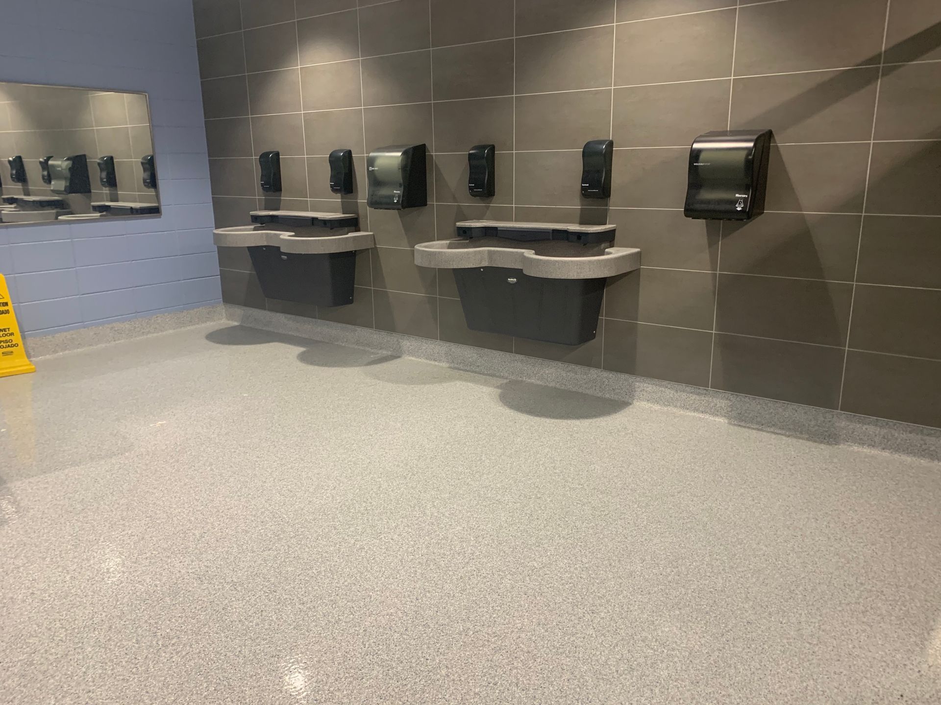 a bathroom with a yellow caution sign on the floor