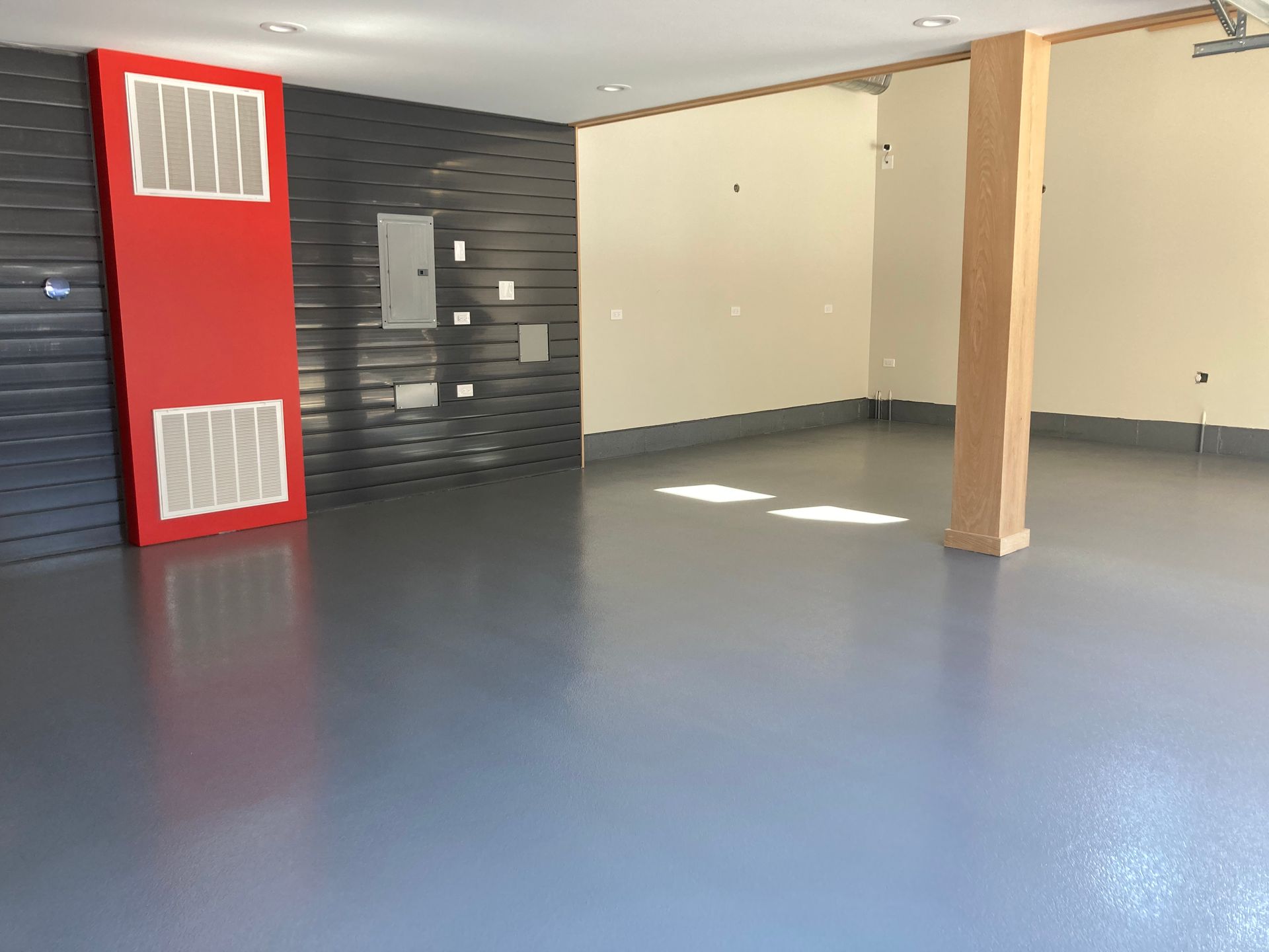 a large empty room with a gray floor and a red wall