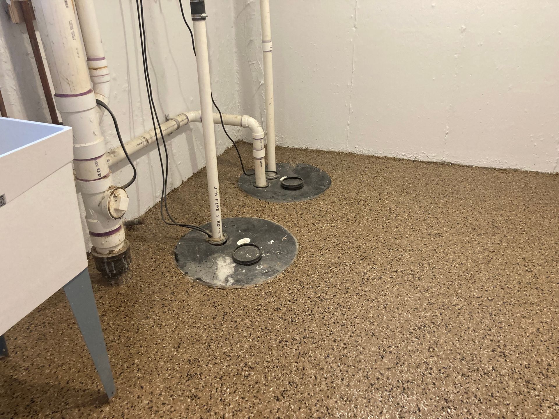 a basement with a concrete floor, pipes, and a sink