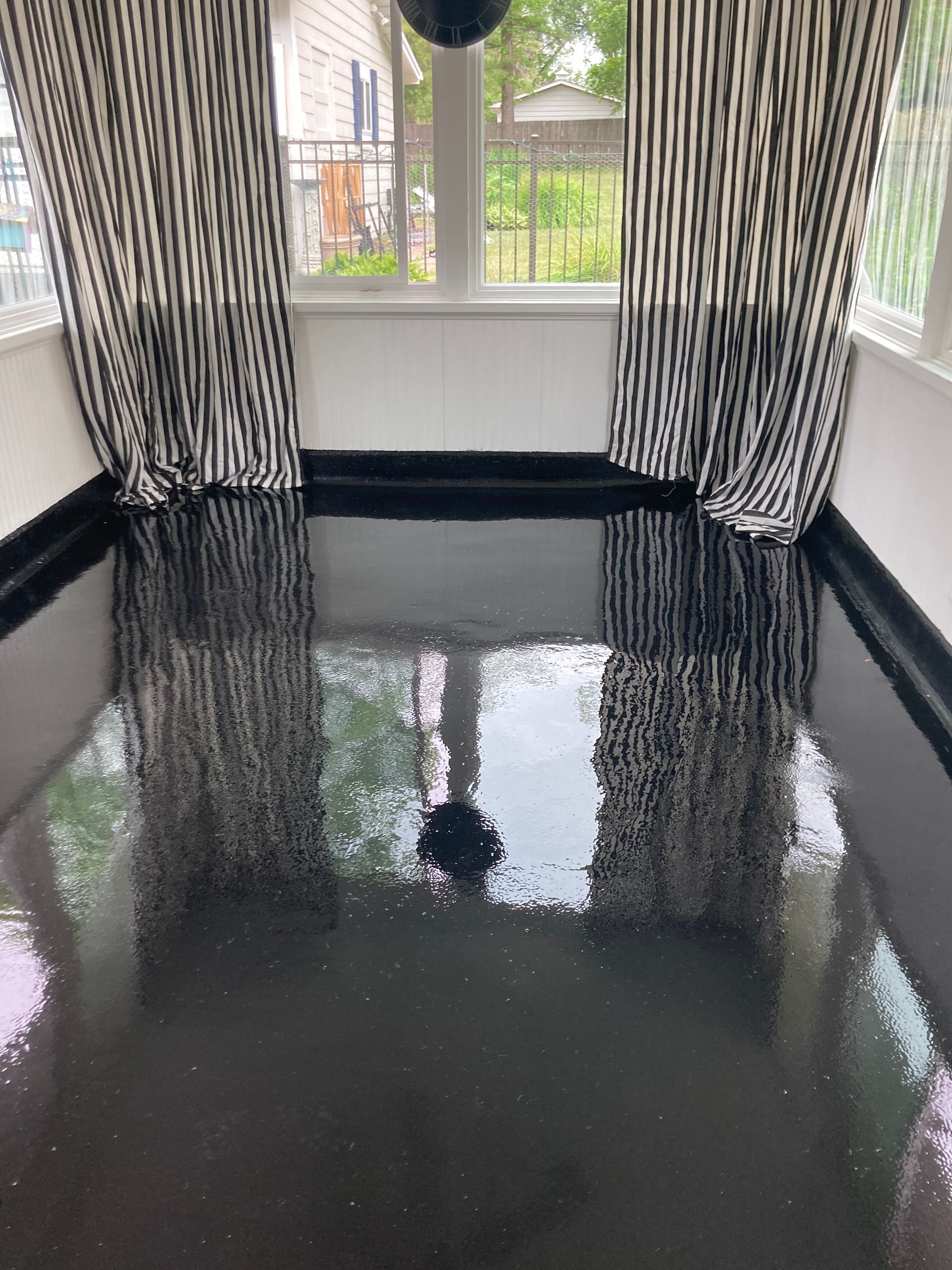 a room with a black floor and black and white curtains