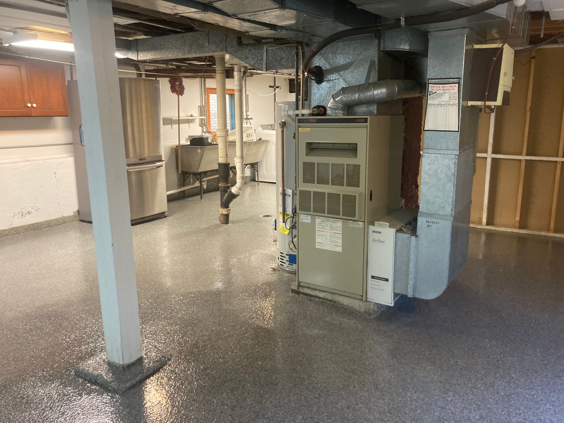 a basement with a heater and a refrigerator in it