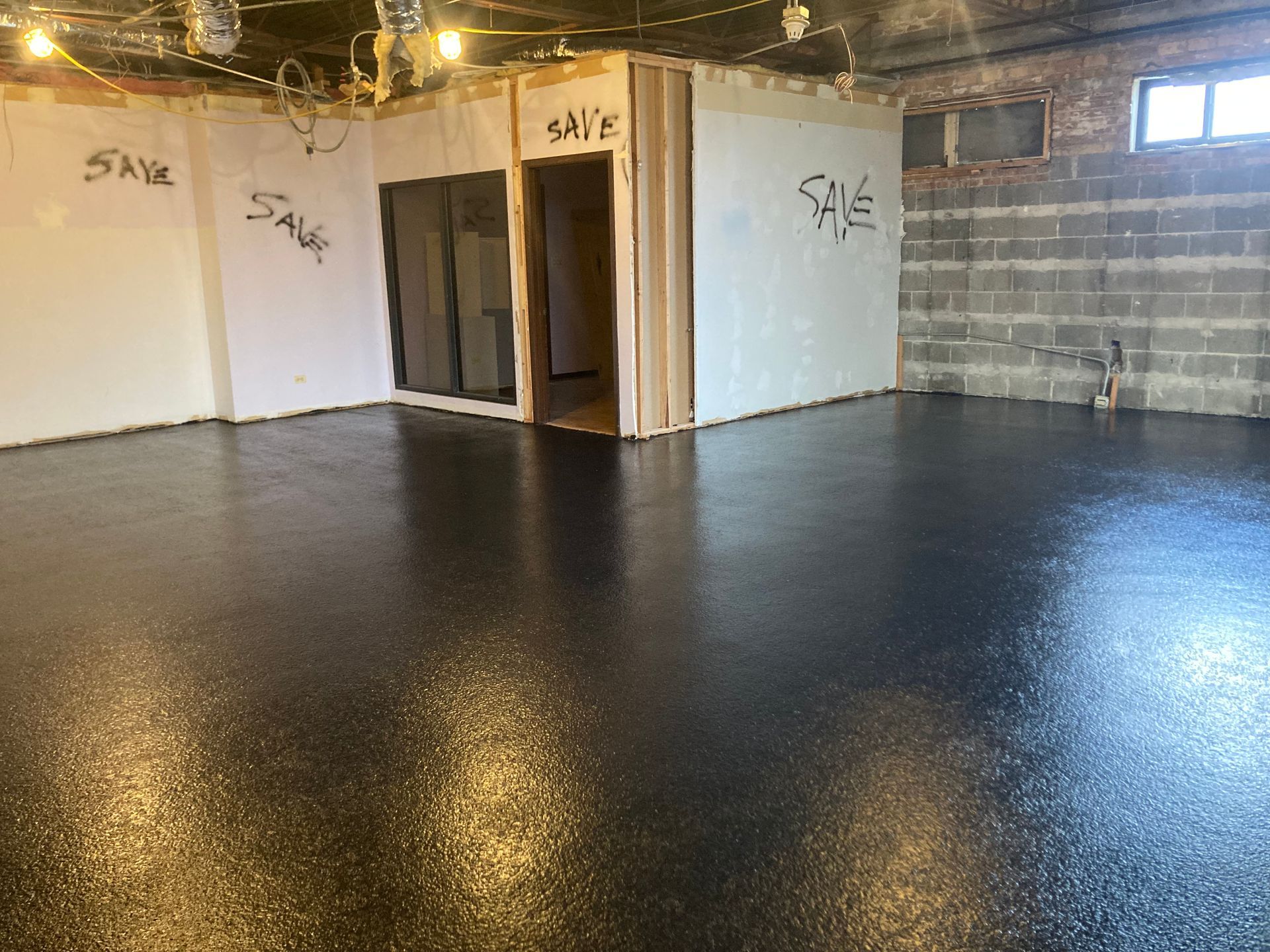 a room with a black floor and a white wall that says save