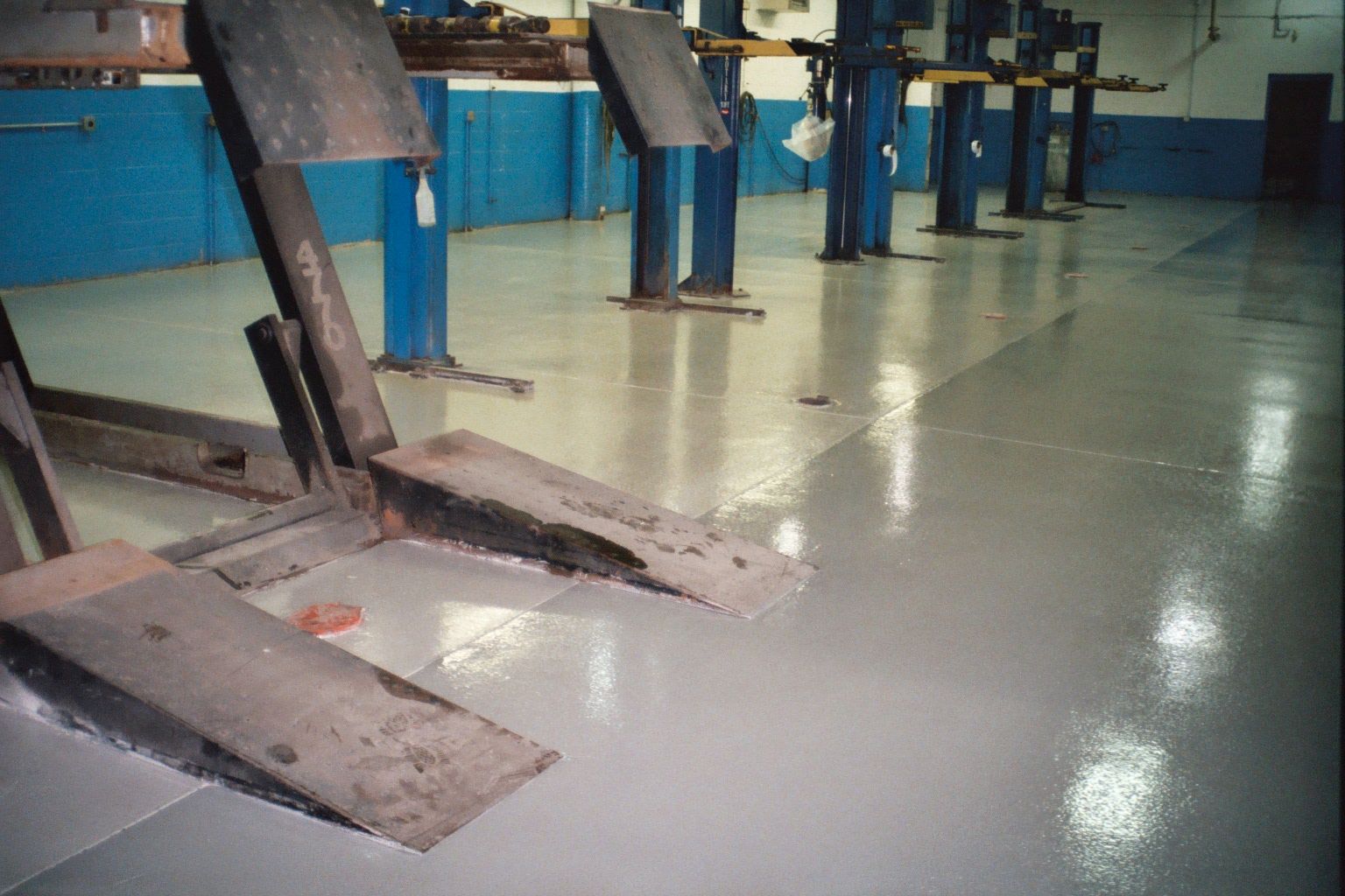 a row of lifts in a garage with a broken lift in the middle