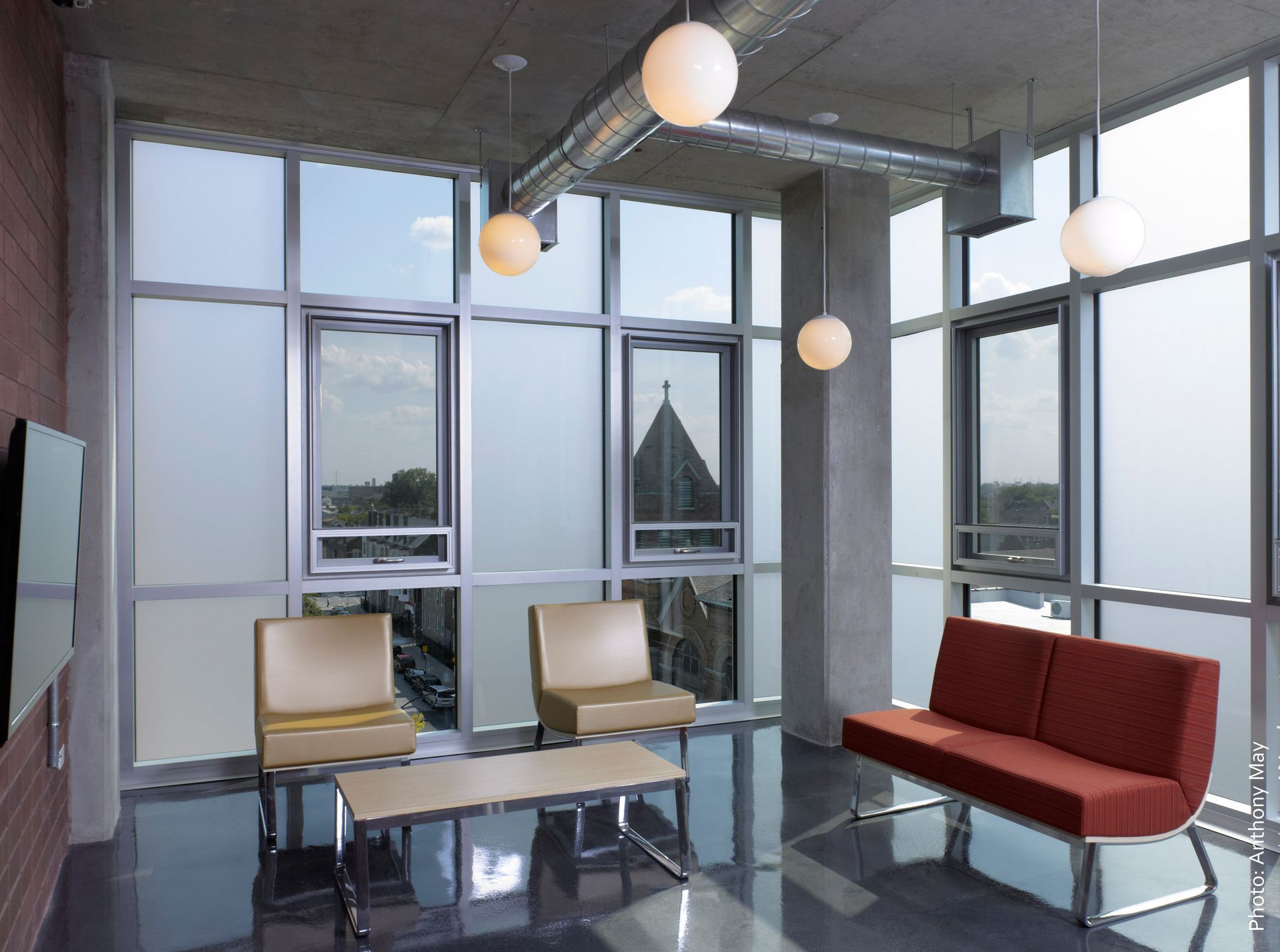 a living room with a couch and chairs and lots of windows