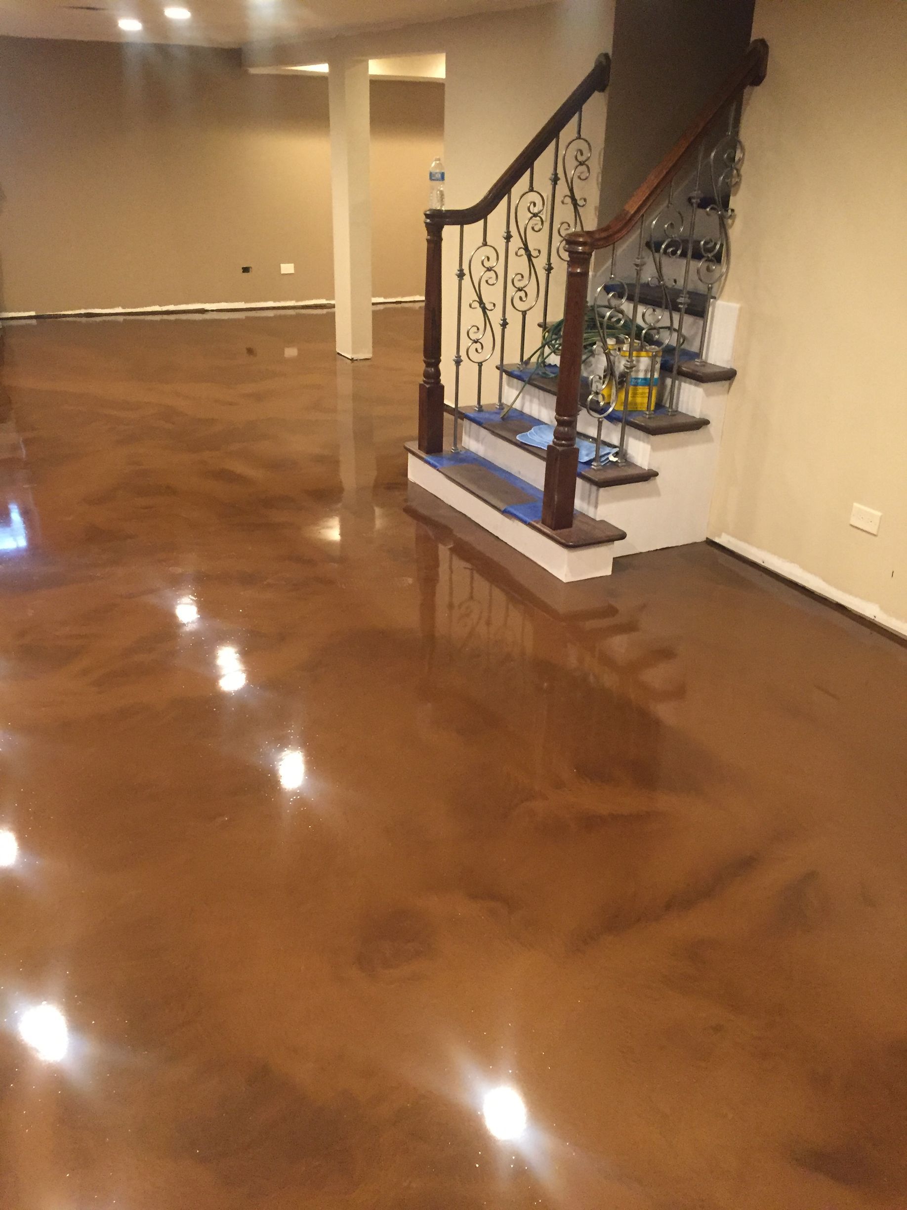 a basement with a staircase and a shiny concrete floor
