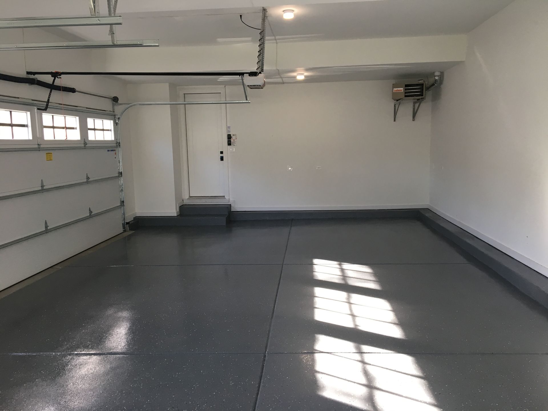 an empty garage with a gray floor and white walls