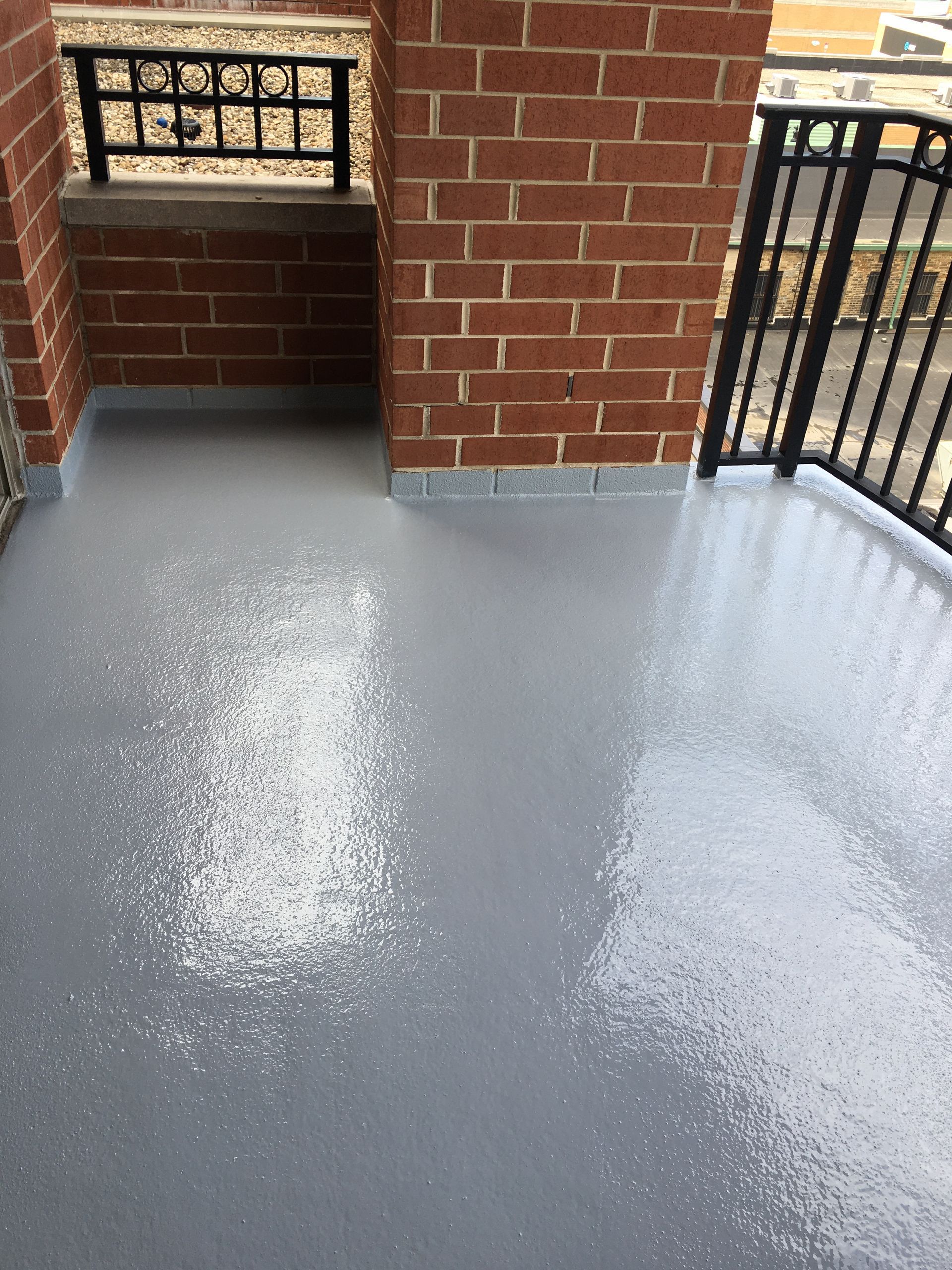 a balcony with a brick wall and a gray floor