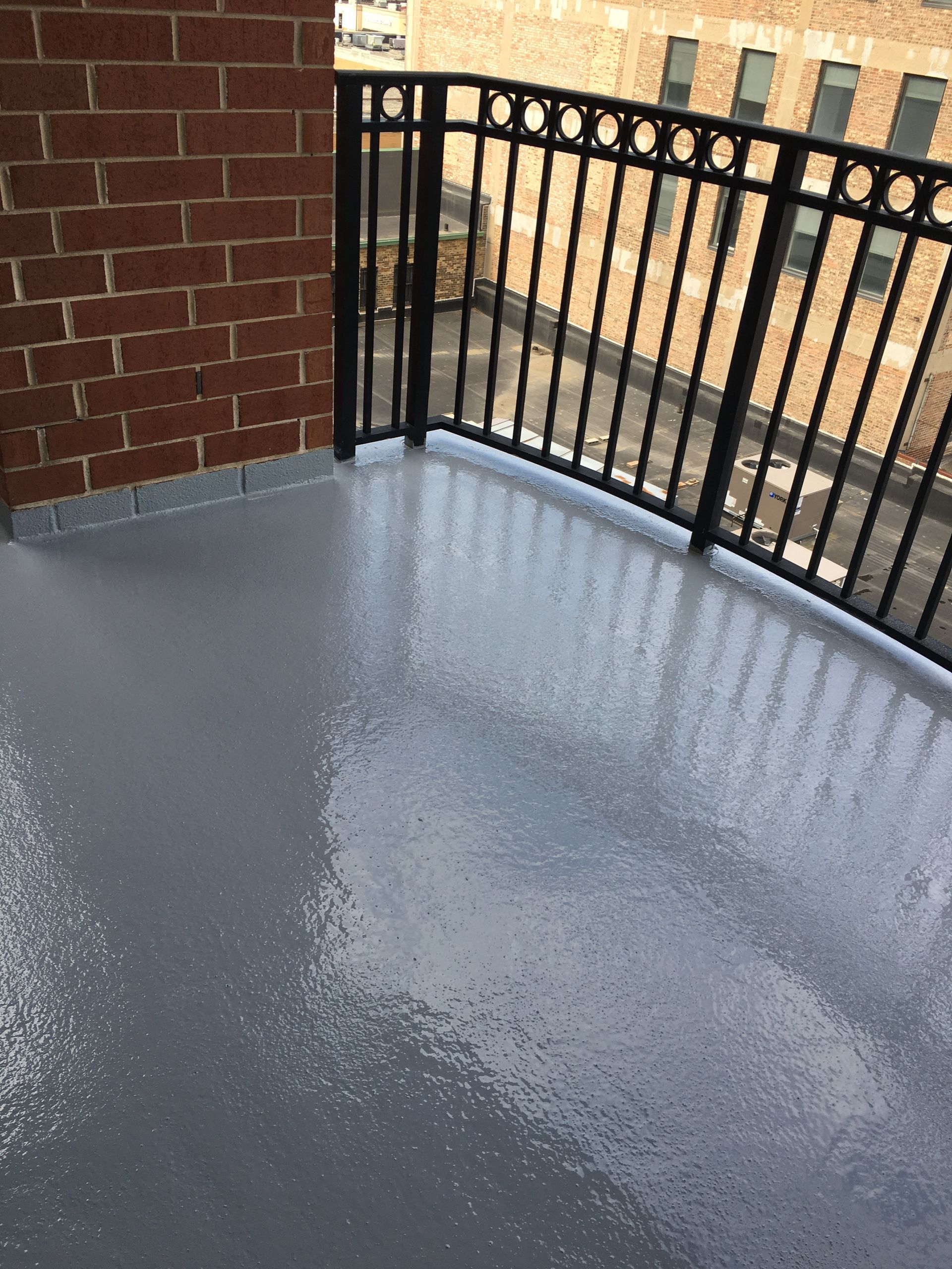 a balcony with a metal railing and a brick wall