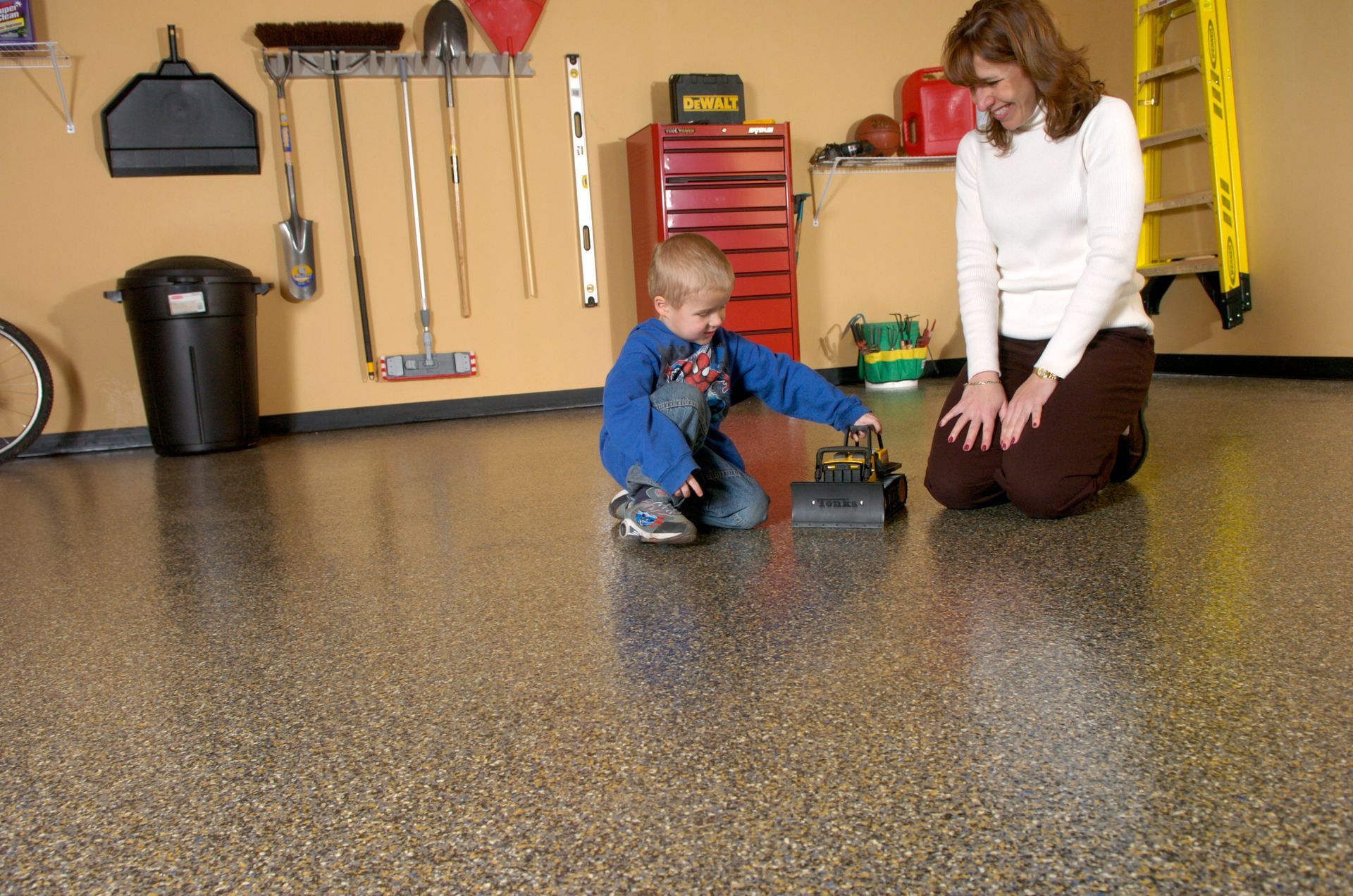 a woman and child are playing with a toy car in a garage