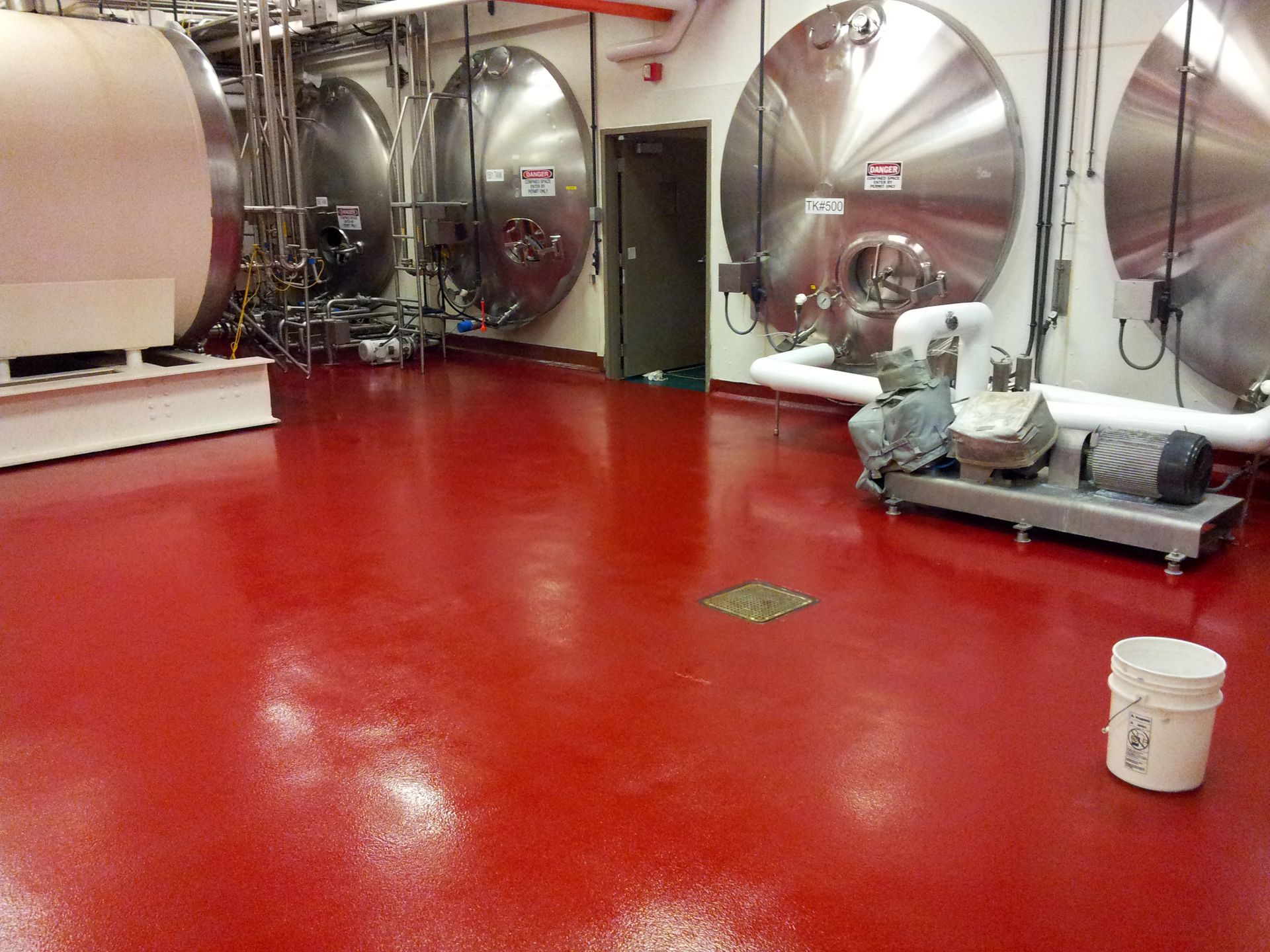 a large room with a red floor and stainless steel tanks