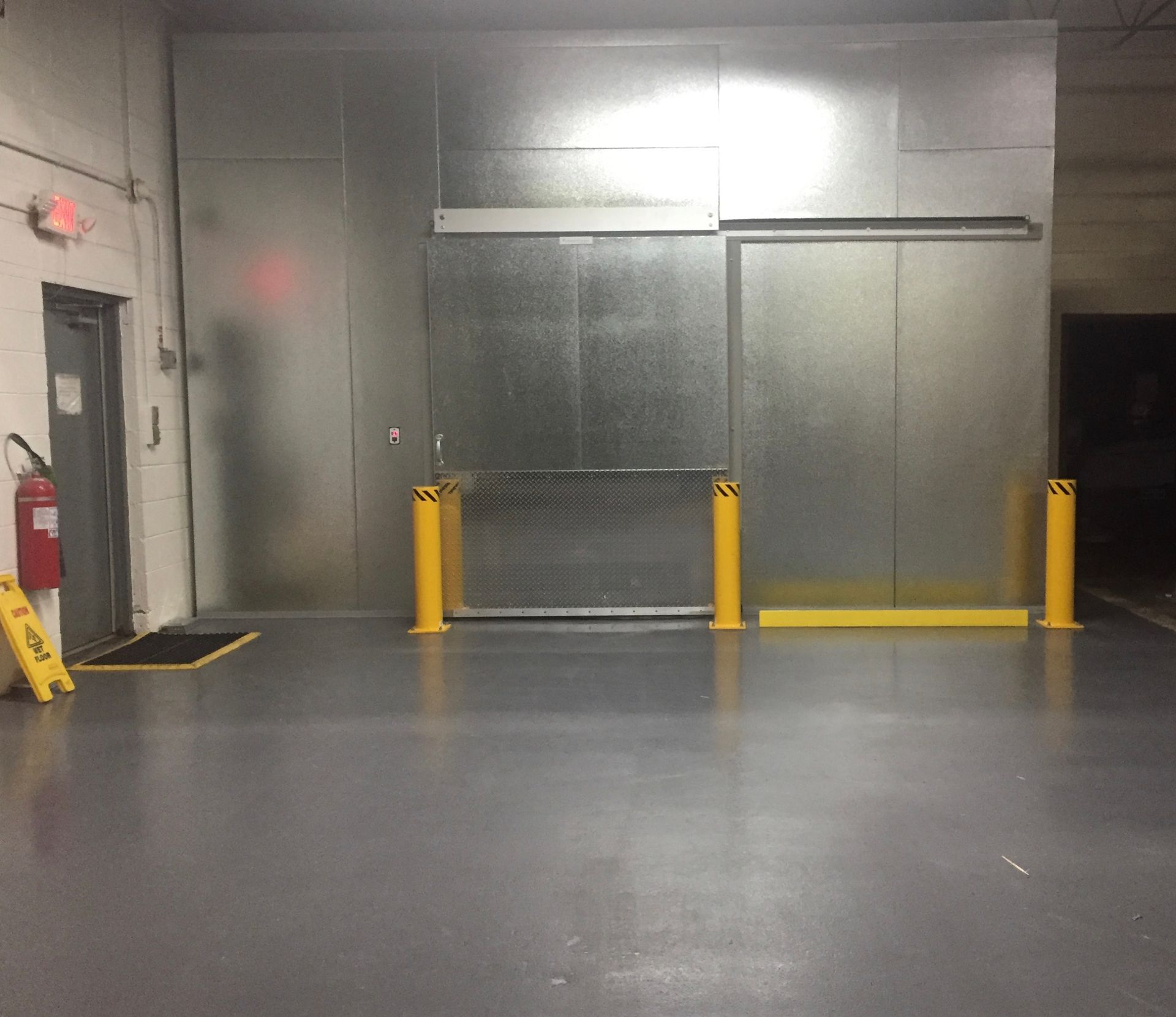 a warehouse with a sliding door and yellow poles