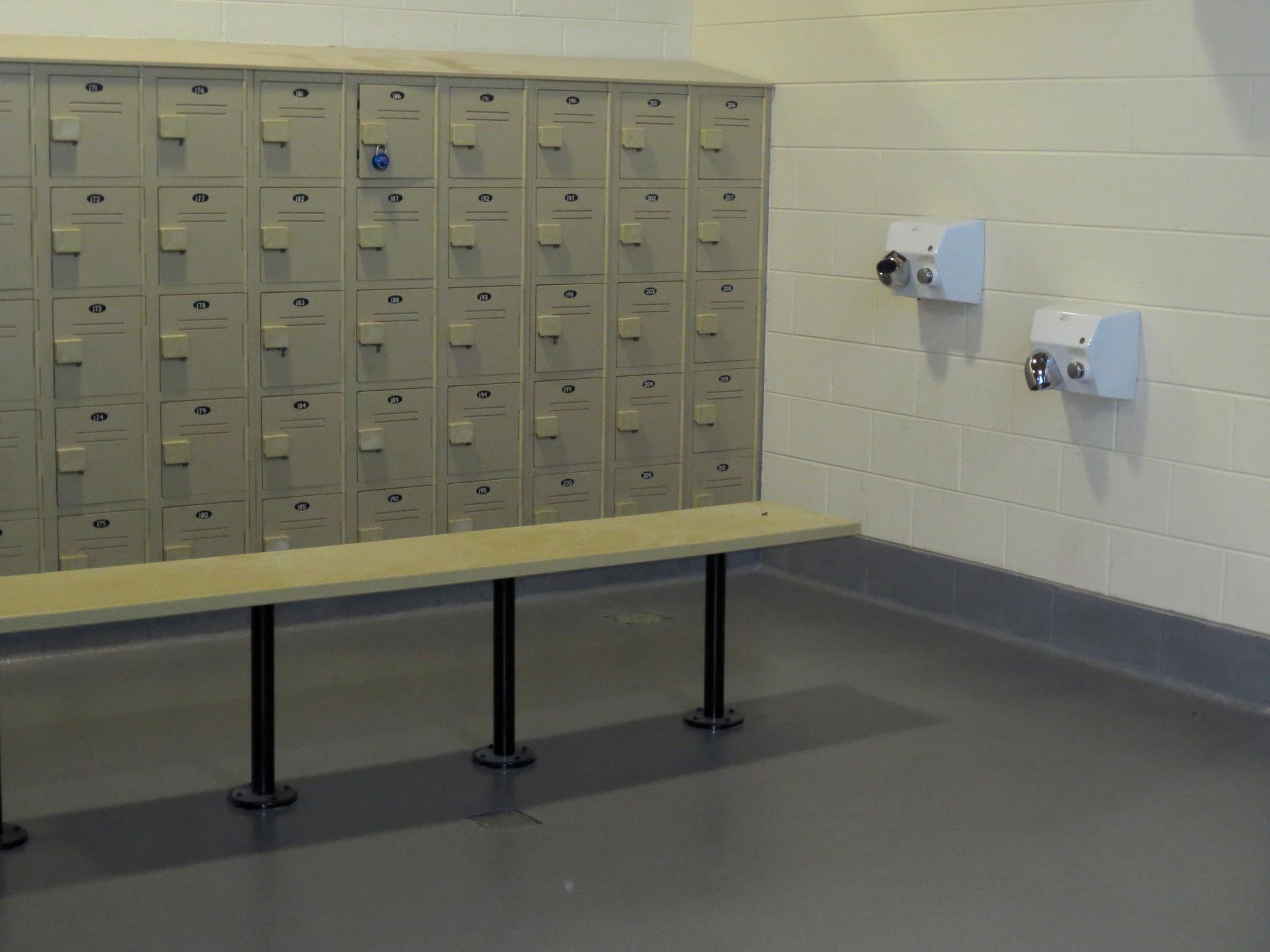 a locker room with a bench and hand dryers