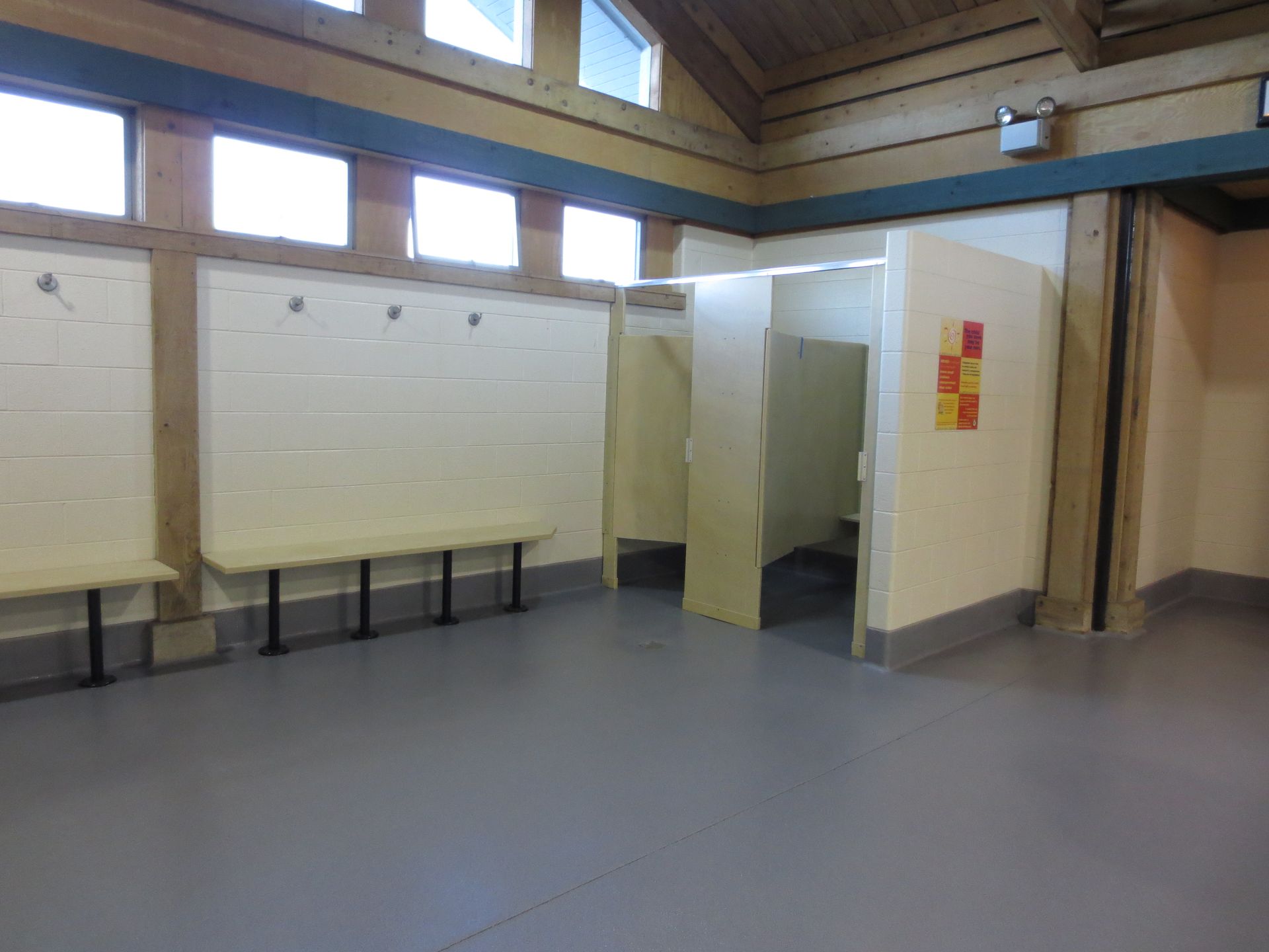 an empty room with a row of toilets and a bench