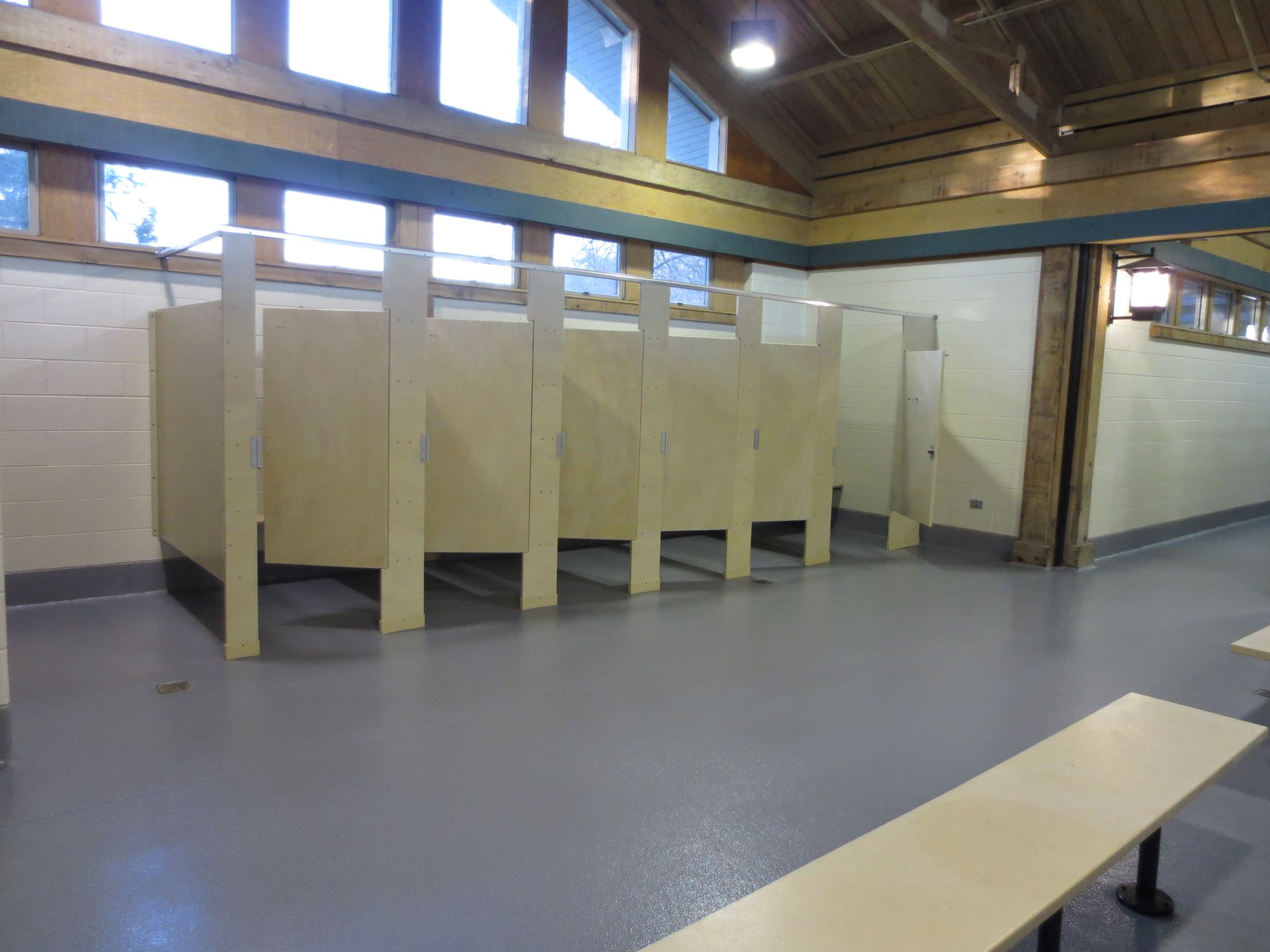 a bathroom with a bench and a row of stalls