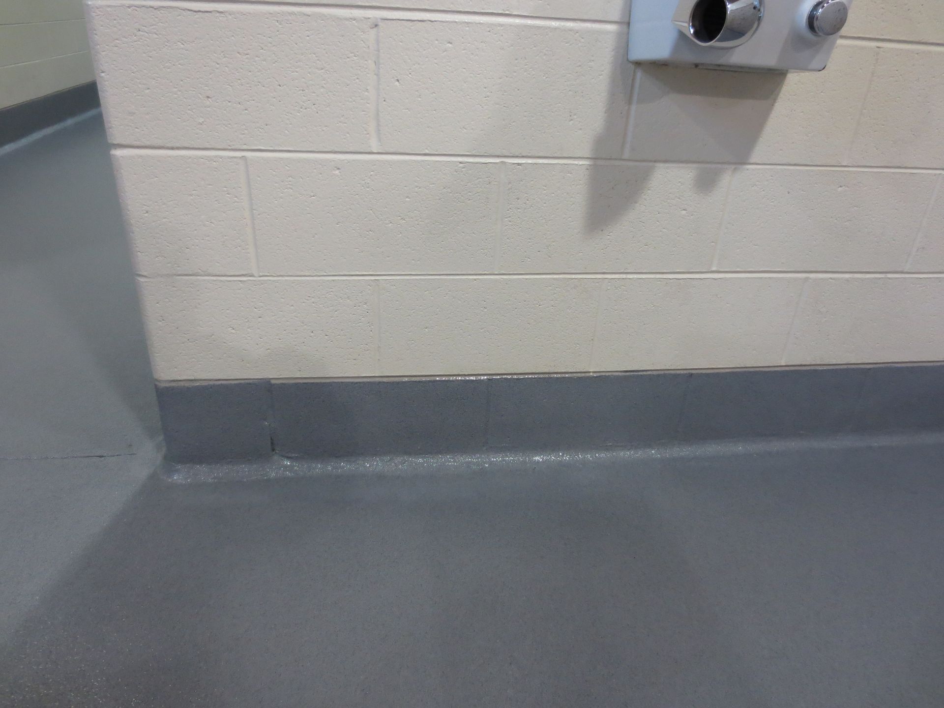 a bathroom with a gray floor and a white brick wall